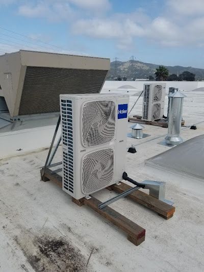 A large air conditioner is sitting on top of a white roof.