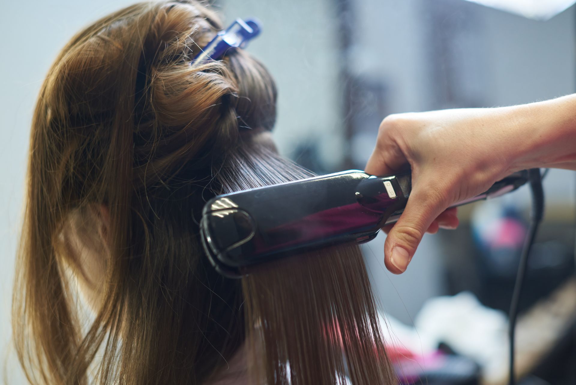 A woman is getting her hair straightened by a hairdresser.