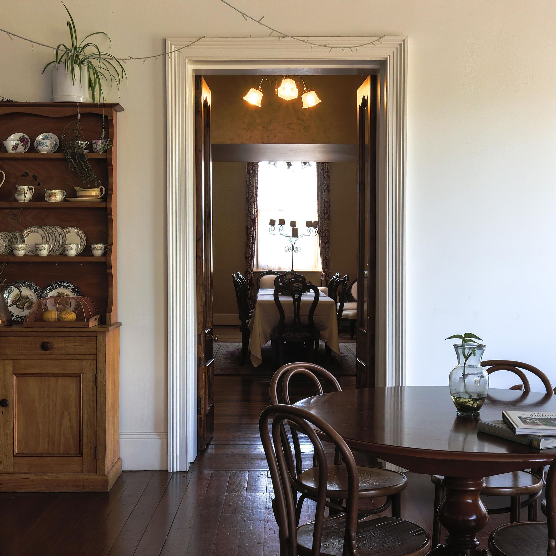 A dining room with a table and chairs and a hutch full of plates