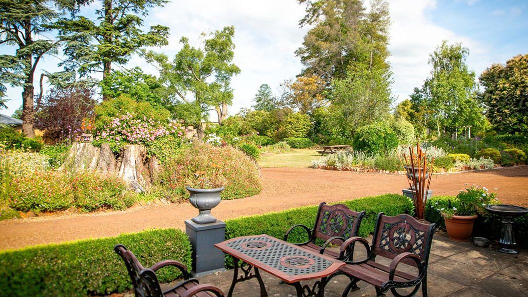 A table and chairs are sitting on the patio in the garden.