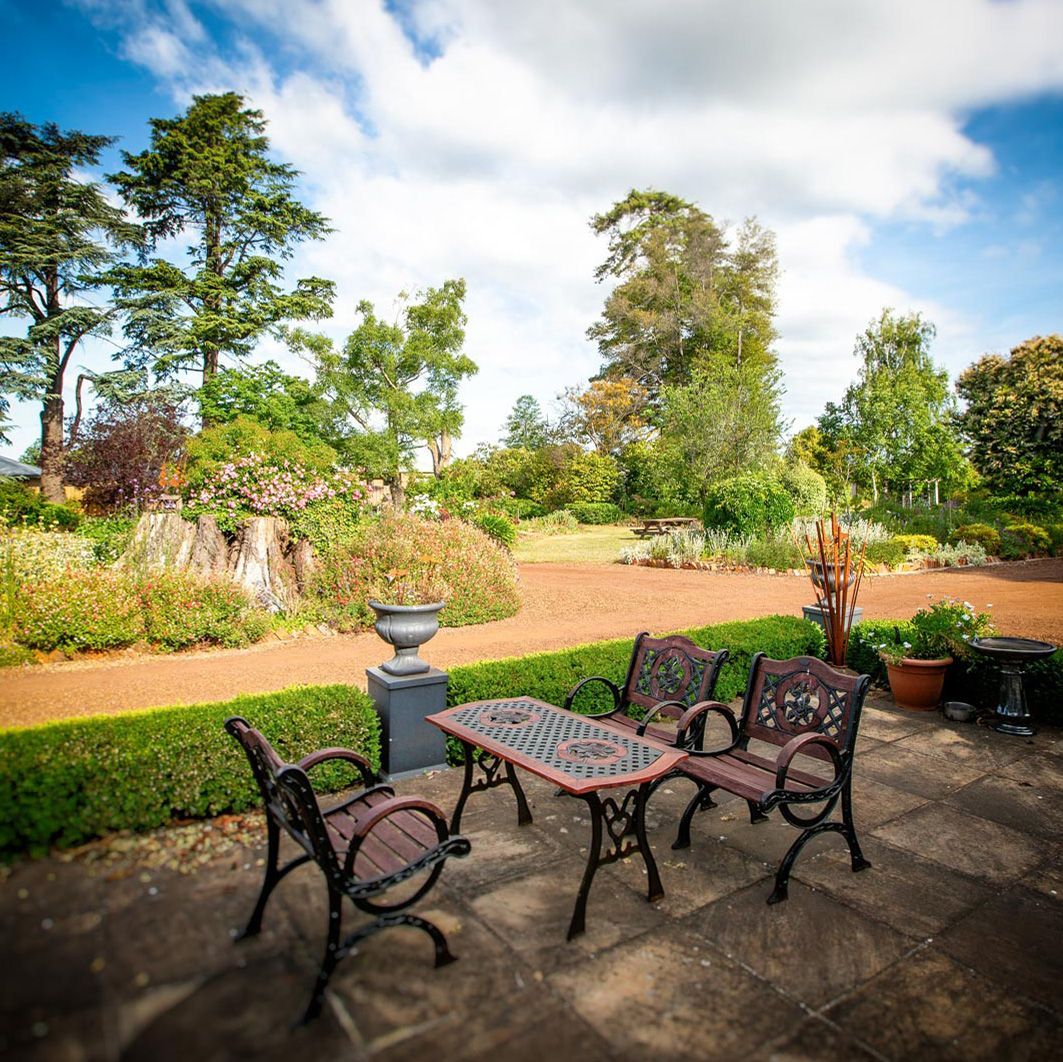 A table and chairs are sitting on a patio in a garden.