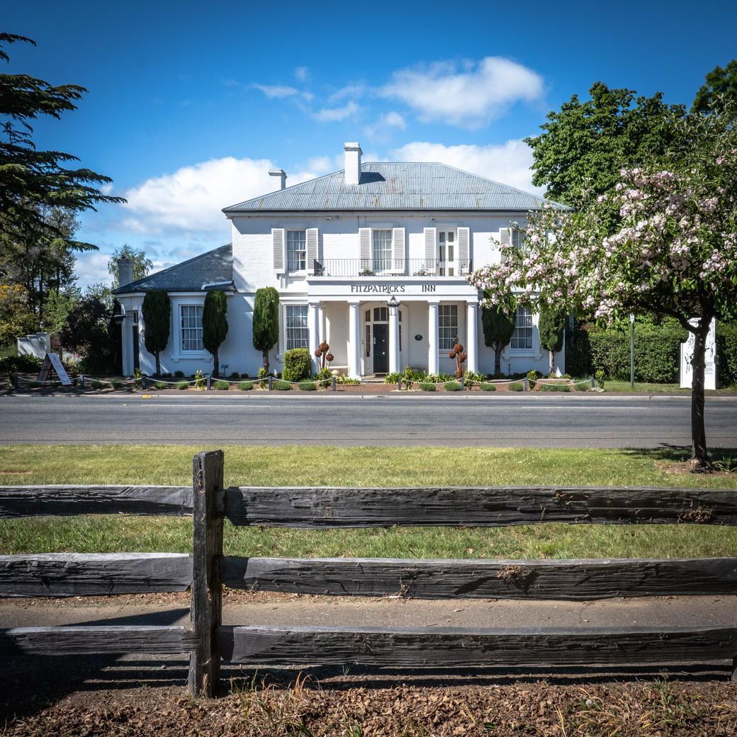 The fitzpatricks inn from across the road with a wooden fence in front of it.