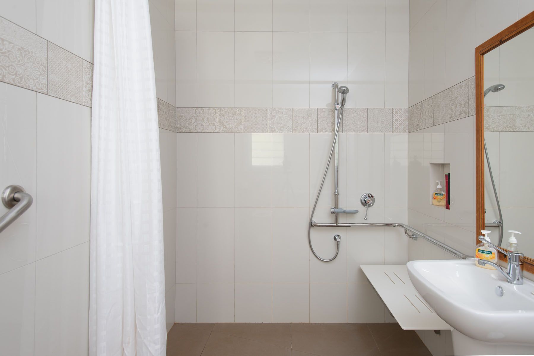 A bathroom with a sink , shower , and mirror.