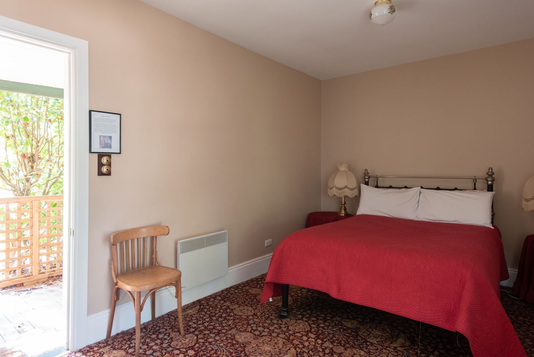 A bedroom with a bed , chair , lamps and a window.