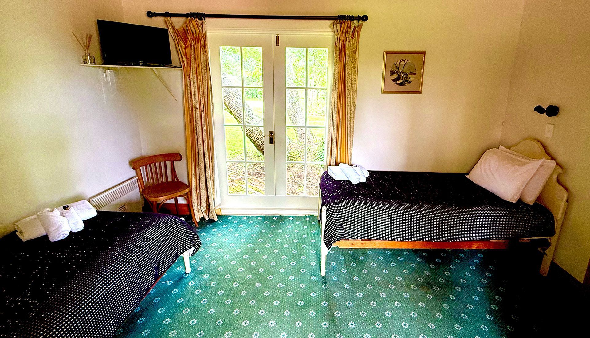 A bedroom with two beds , a chair and a television.