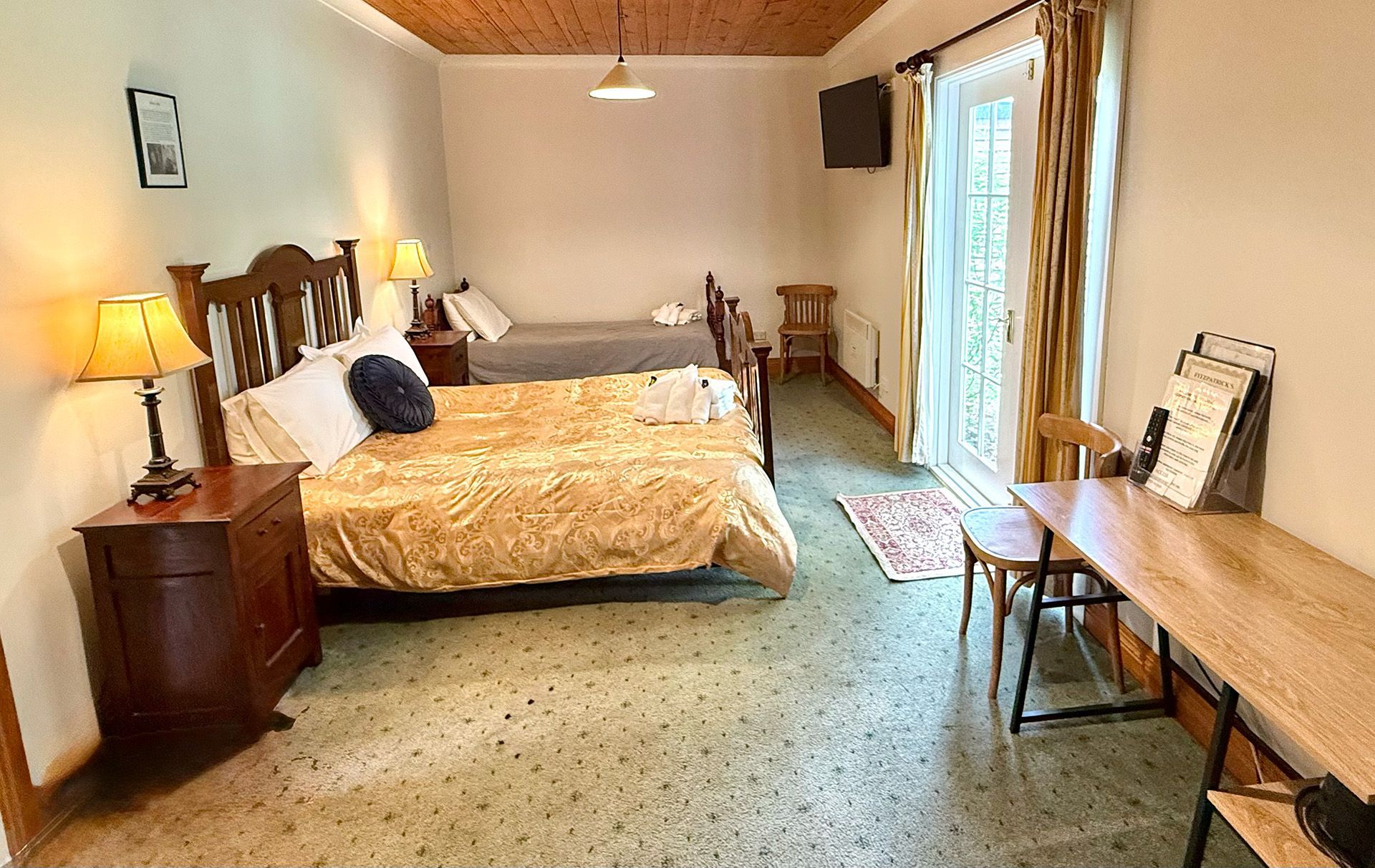 A bedroom with two beds , a desk , and a sliding glass door.