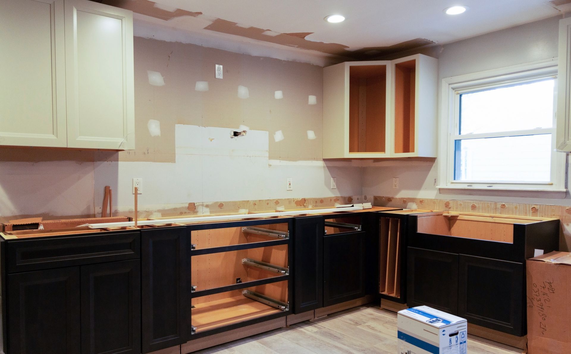 Partially renovated kitchen with dark cabinets, bare walls, and unfinished countertops