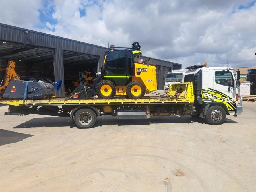 A Tow Truck With a Tractor on the Back is Parked in a Parking Lot — Pro-Tow Toowoomba in Wilsonton, QLD