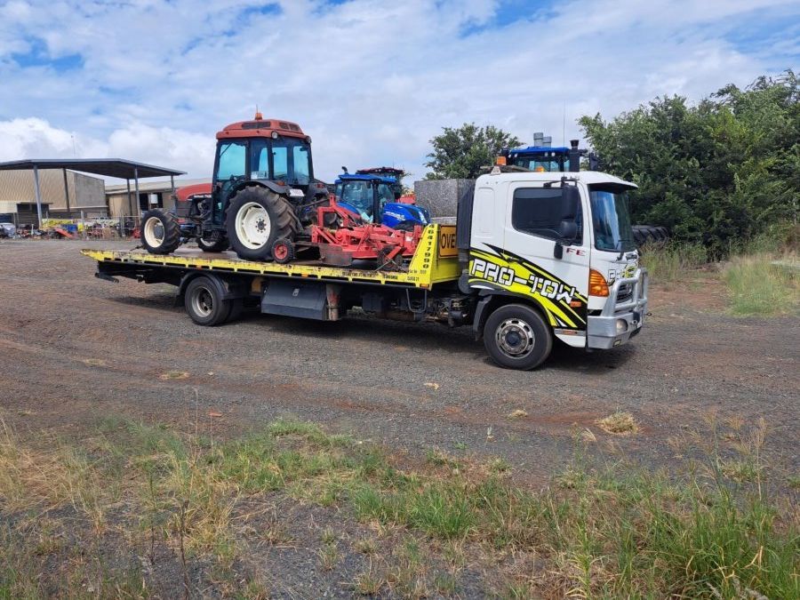 A Tow Truck is Carrying Two Tractors on a Flatbed Trailer — Pro-Tow Toowoomba in Wilsonton, QLD