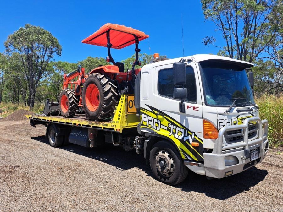 A Tow Truck With a Tractor on the Back of It — Pro-Tow Toowoomba in Wilsonton, QLD