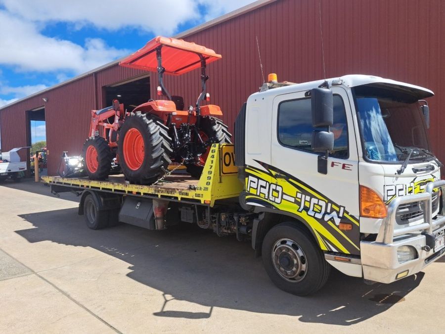 A Tow Truck is Carrying a Tractor on the Back of It — Pro-Tow Toowoomba in Wilsonton, QLD