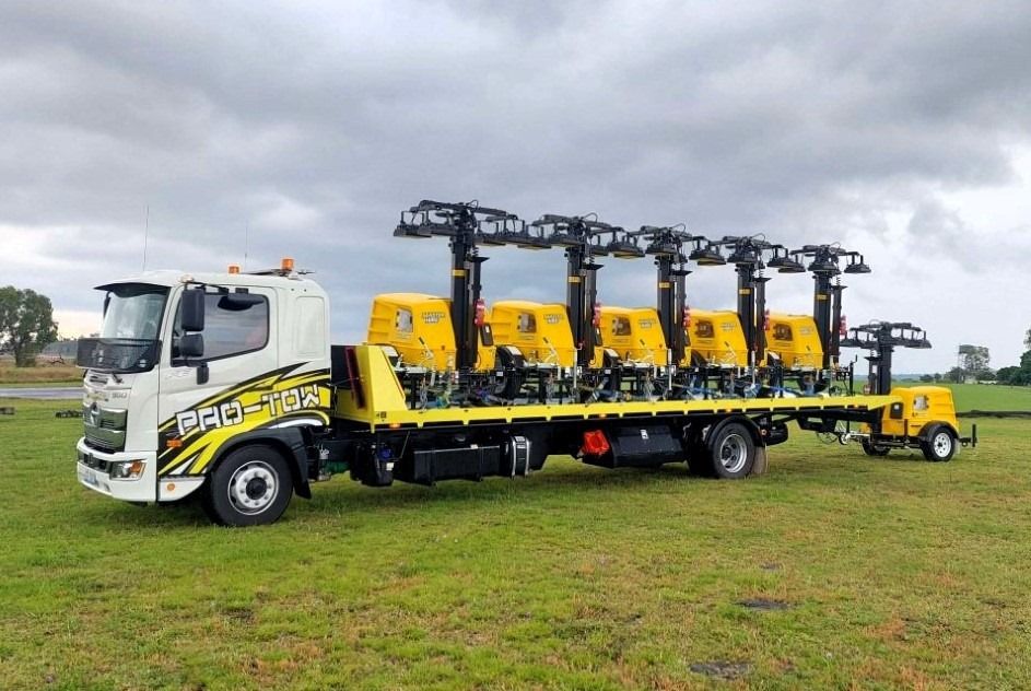 A Tow Truck With a Trailer Attached to It is Parked in a Grassy Field — Pro-Tow Toowoomba in Wilsonton, QLD
