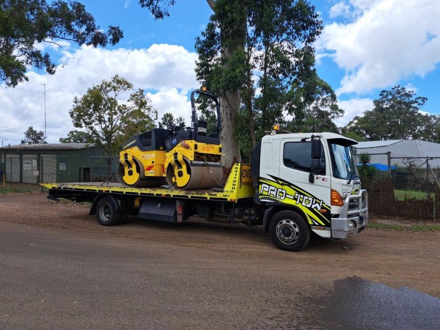 A Tow Truck is Carrying a Yellow Roller on the Back of It — Pro-Tow Toowoomba in Wilsonton, QLD
