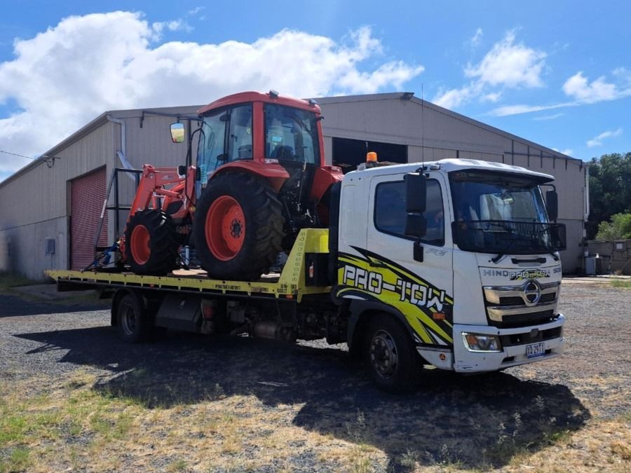 A Tow Truck is Carrying a Tractor on the Back of It — Pro-Tow Toowoomba in Wilsonton, QLD