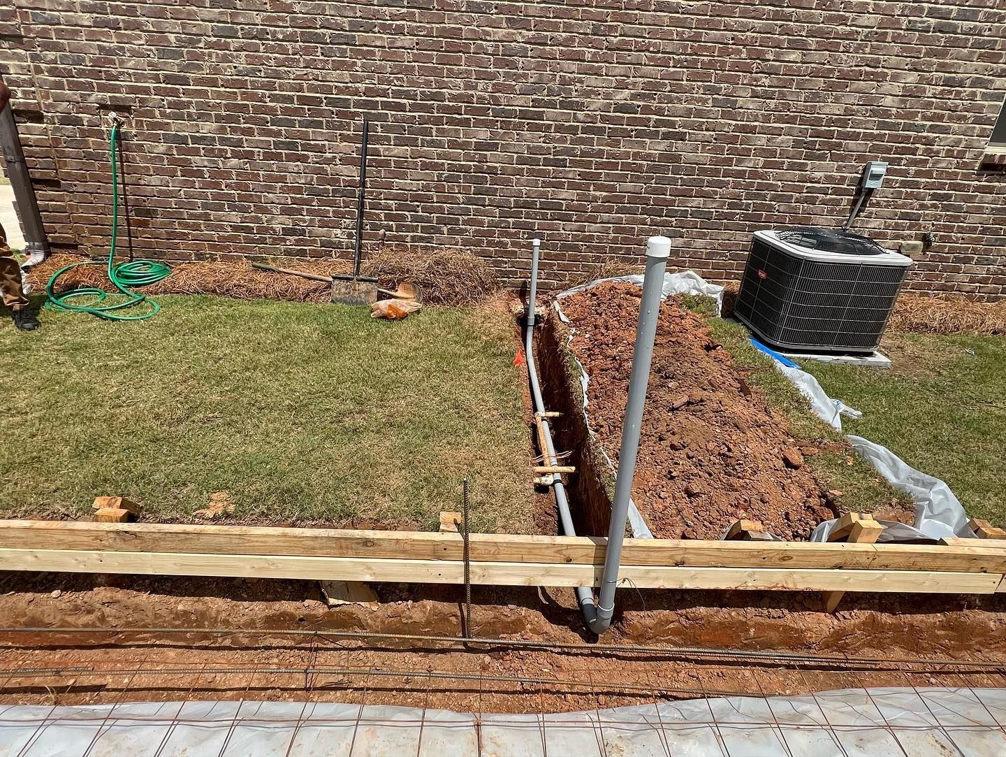 A brick wall is being built in the backyard of a house.