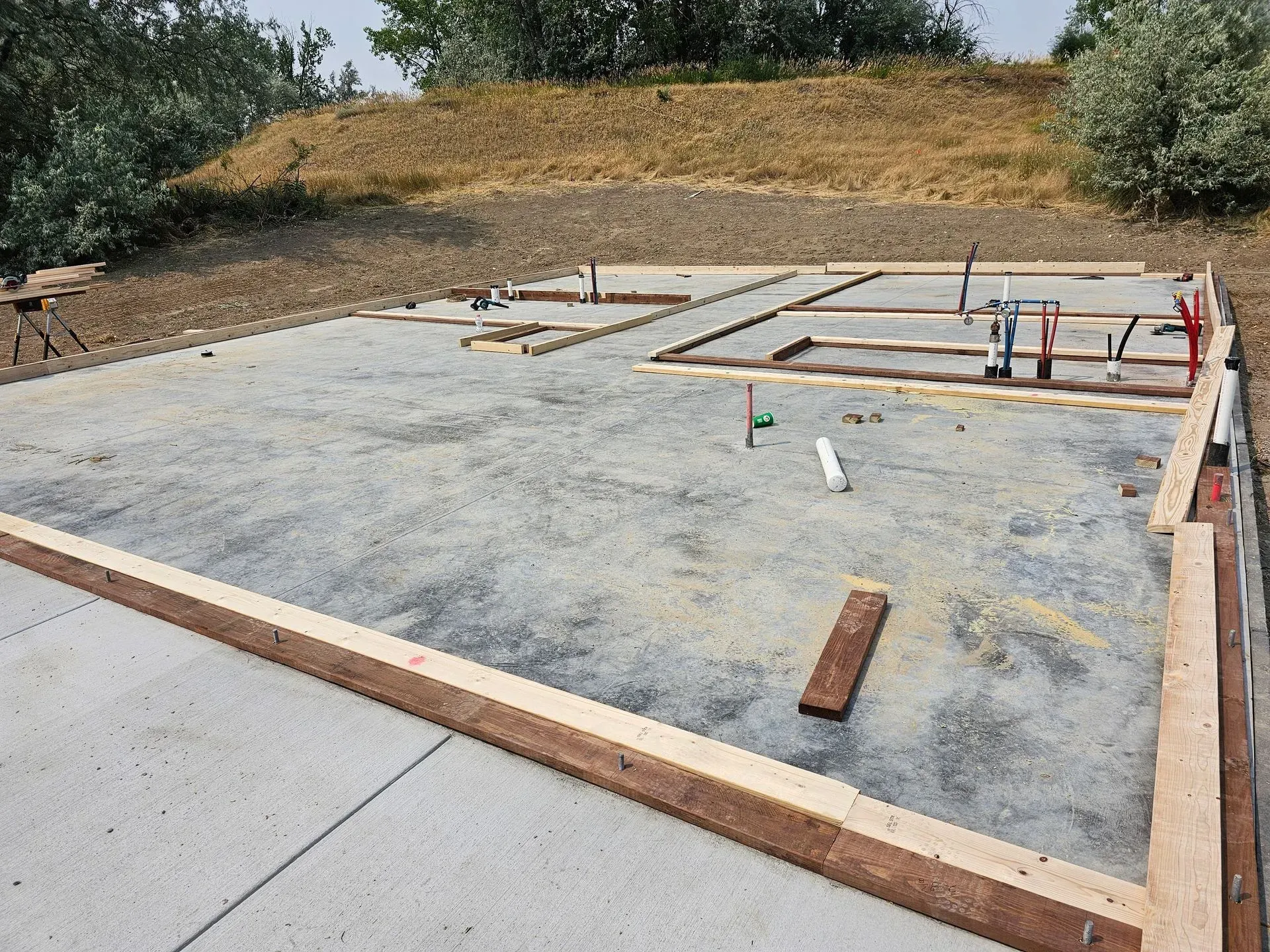 A concrete base for a house is being built in a field.