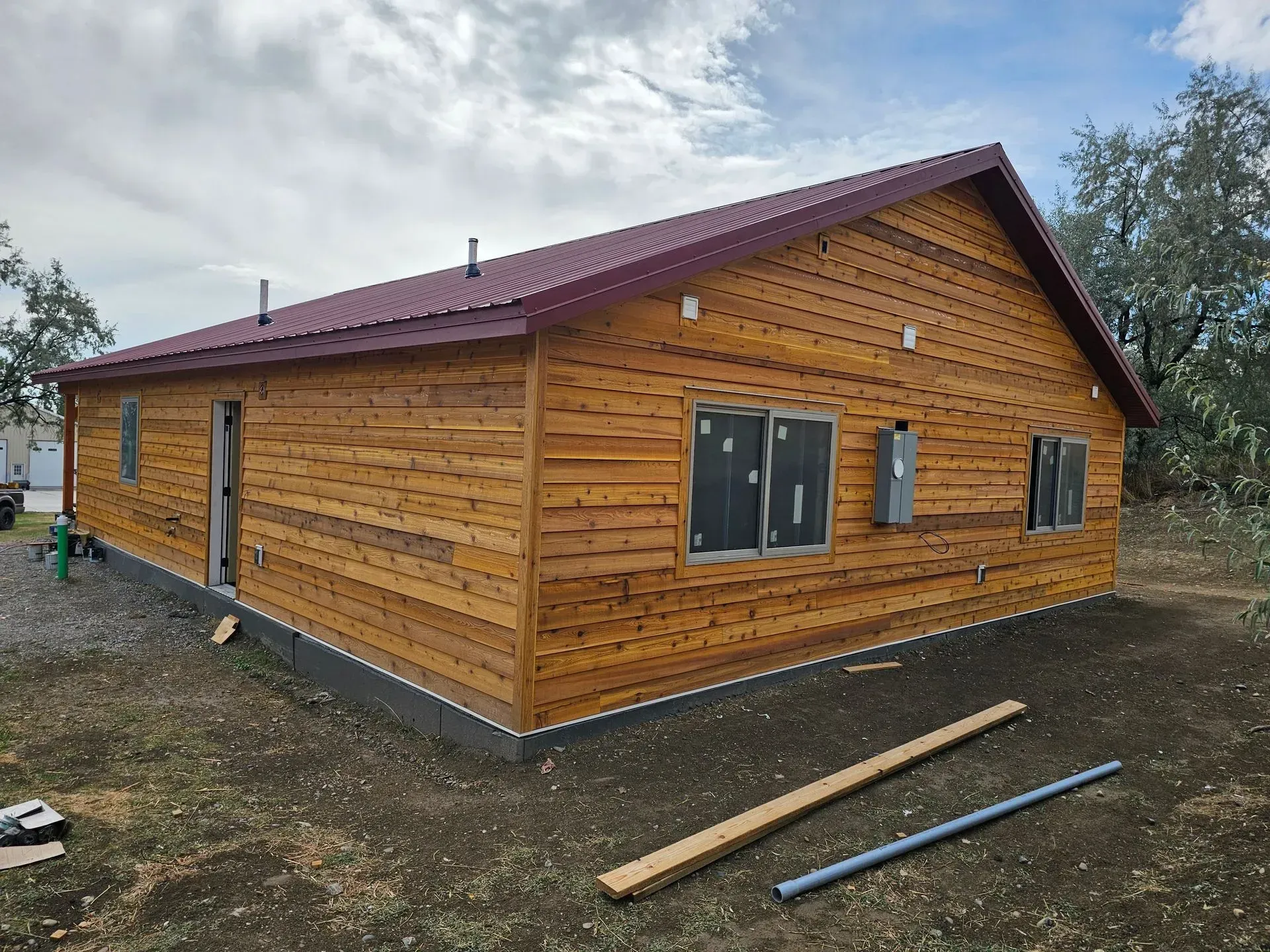 A large wooden house with a red roof is being built.