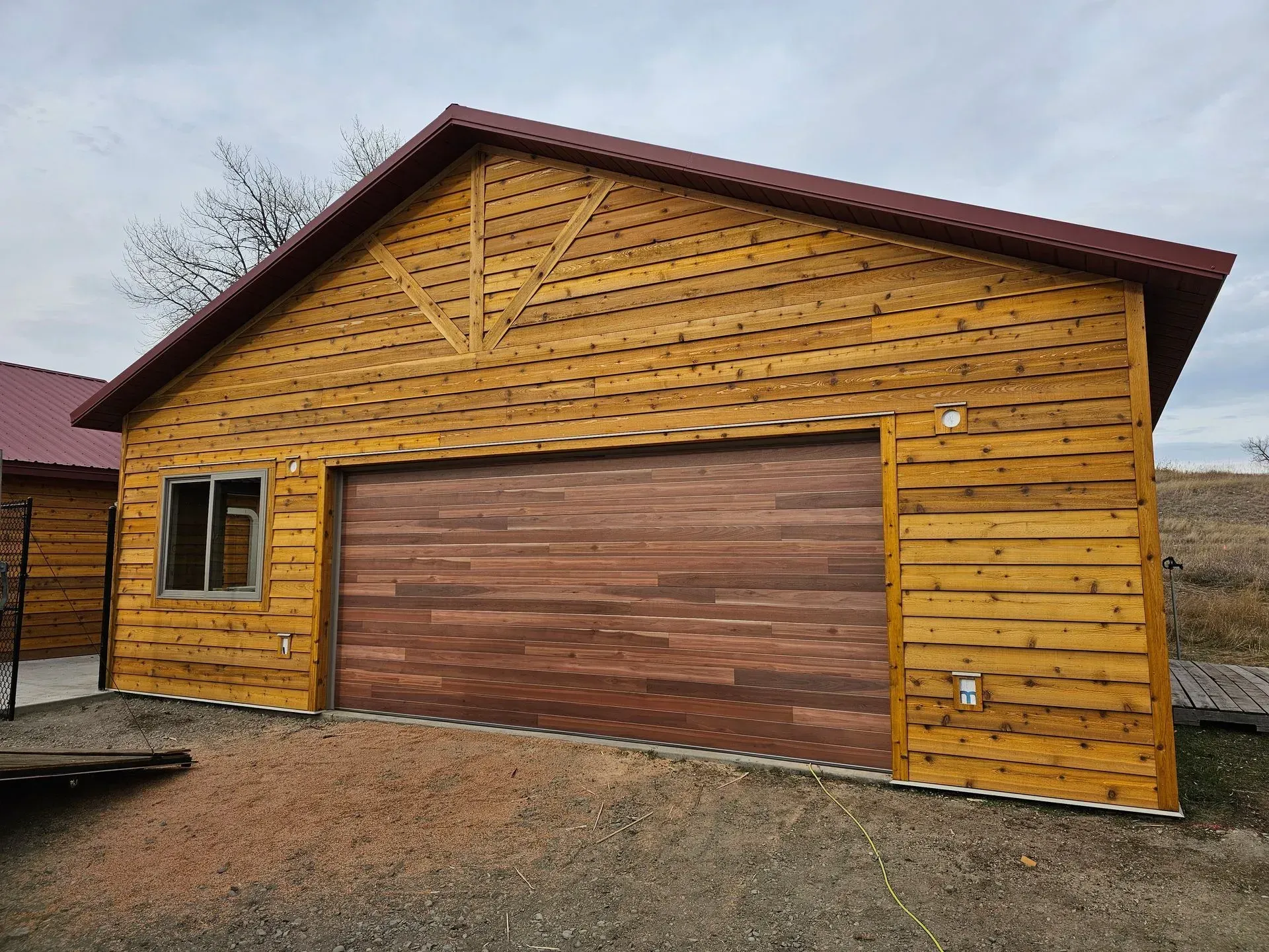 A wooden garage with a brown garage door and a window.