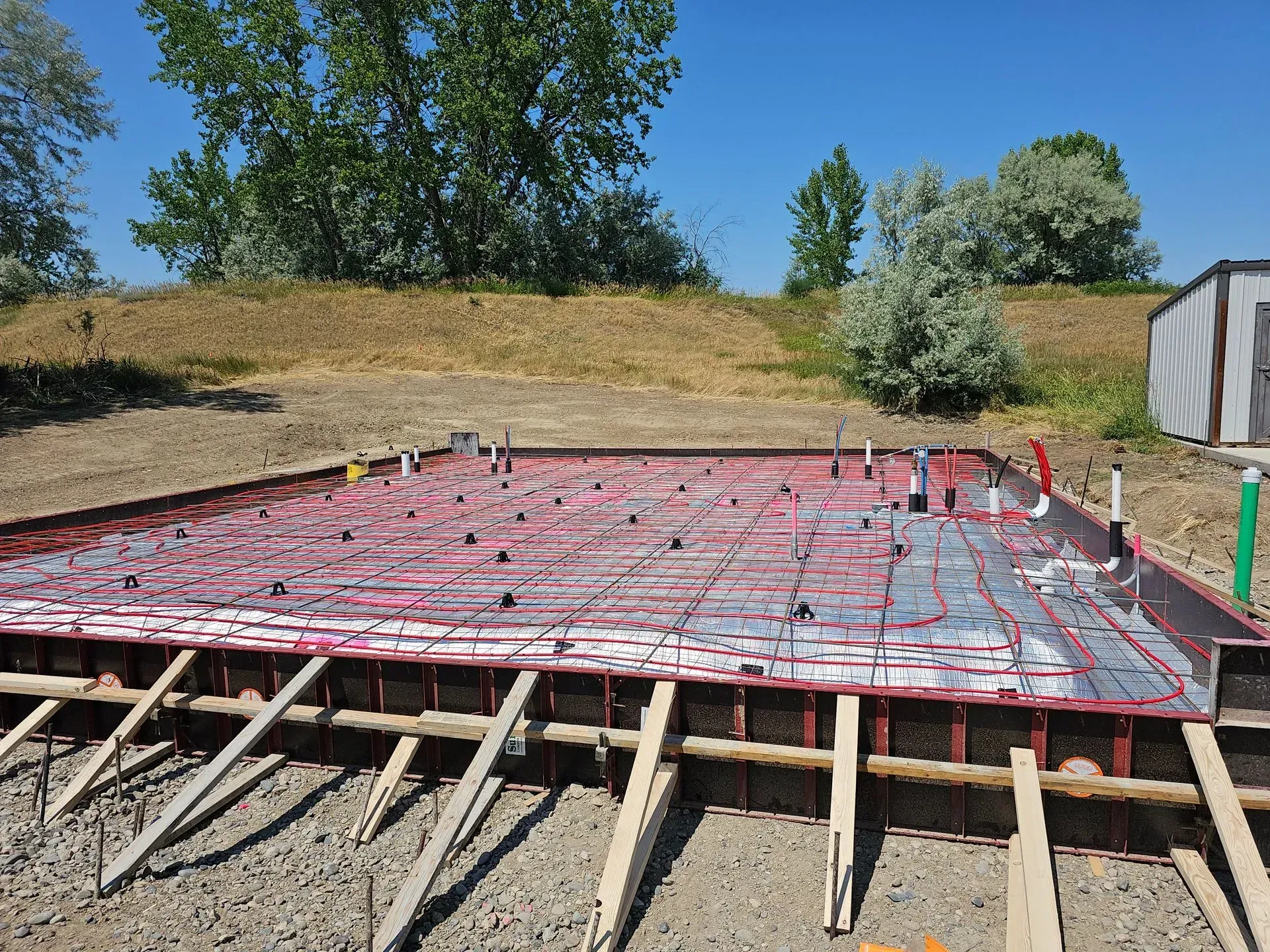 A concrete foundation is being built in a dirt field.