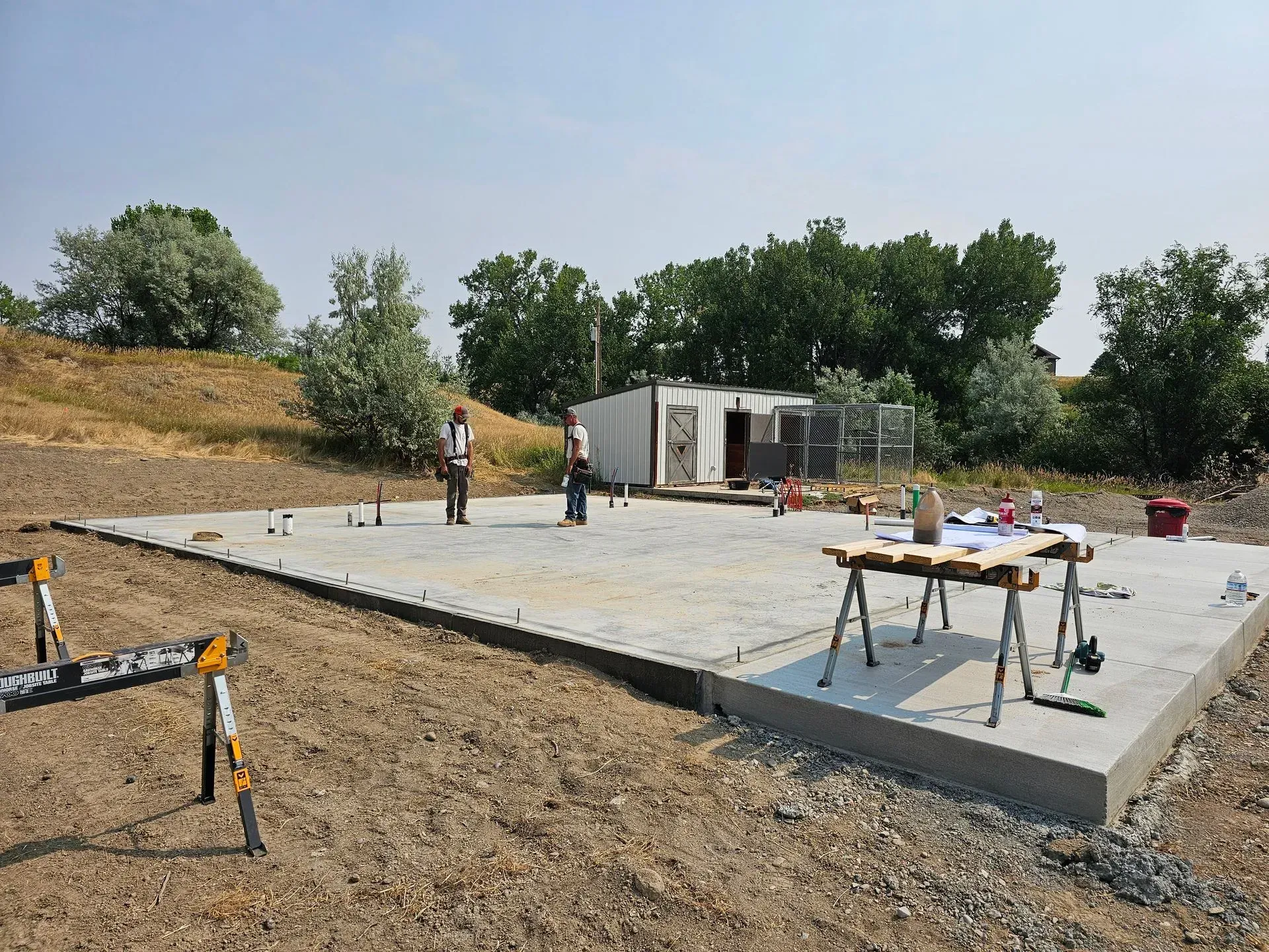 A concrete base is being built in a dirt field