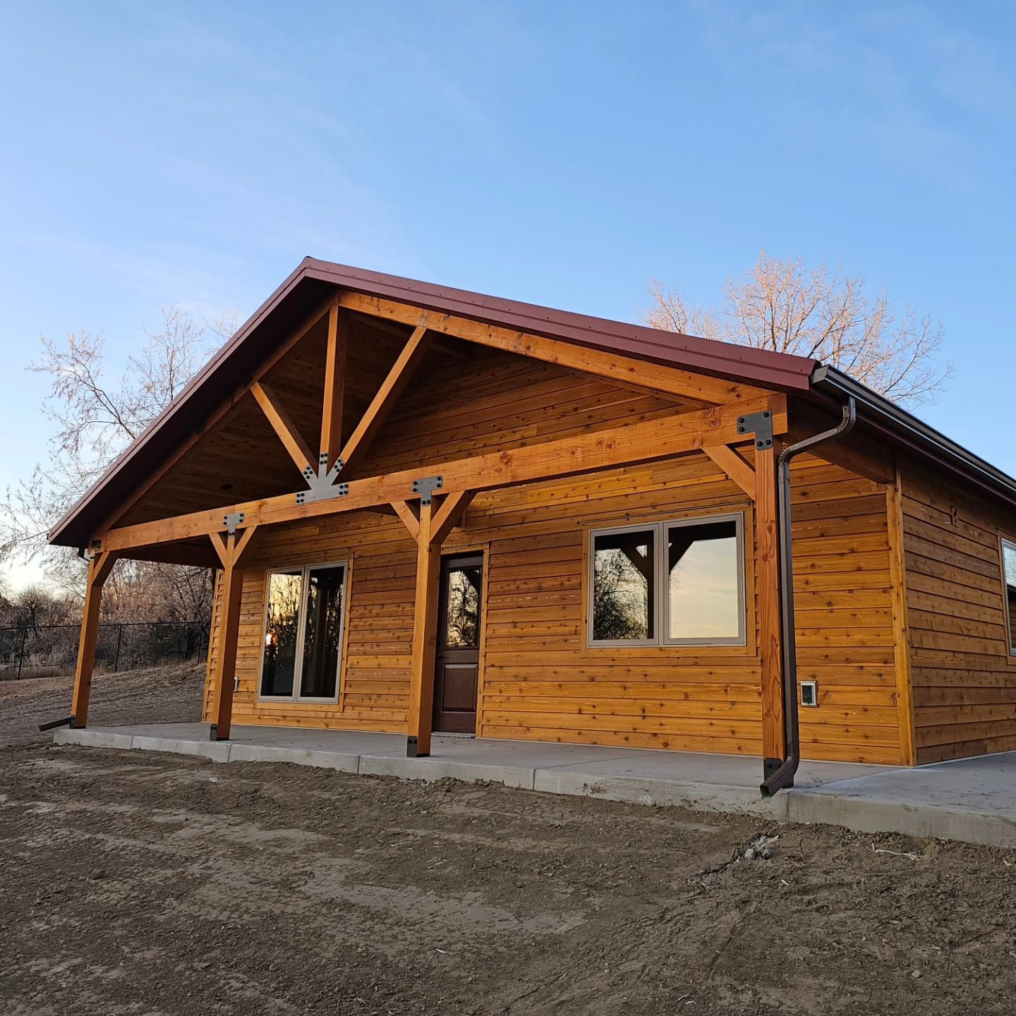 A wooden house with a red roof and a porch