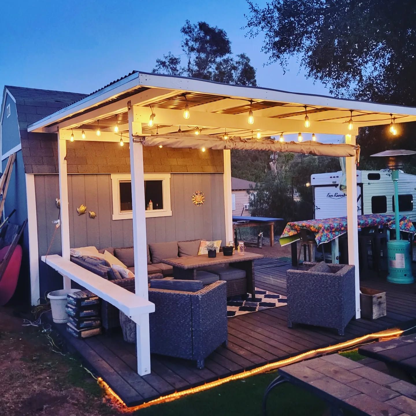 A pergola with a couch and chairs underneath it