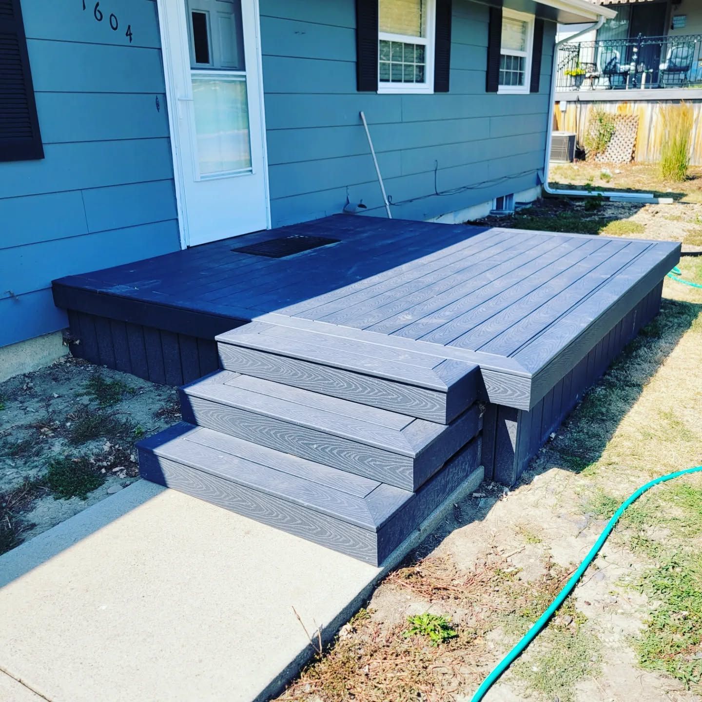 A blue house with a deck and stairs in front of it