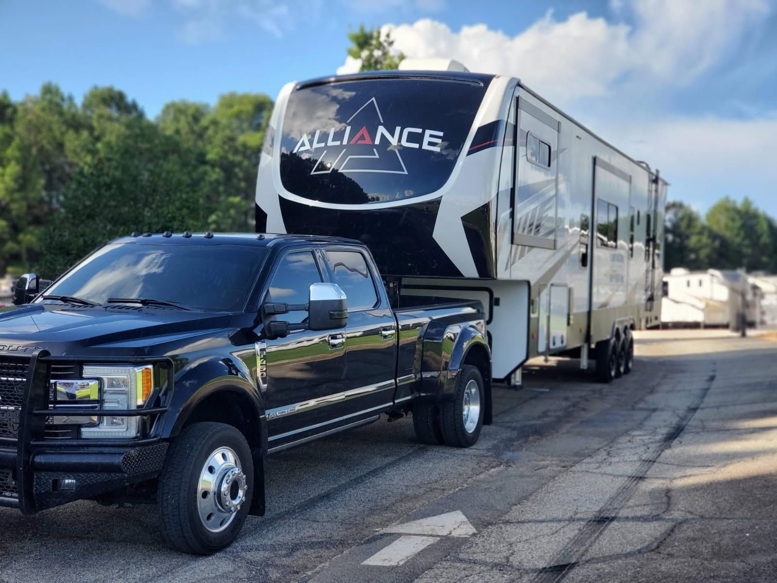 A black truck is towing a trailer that says alliance.