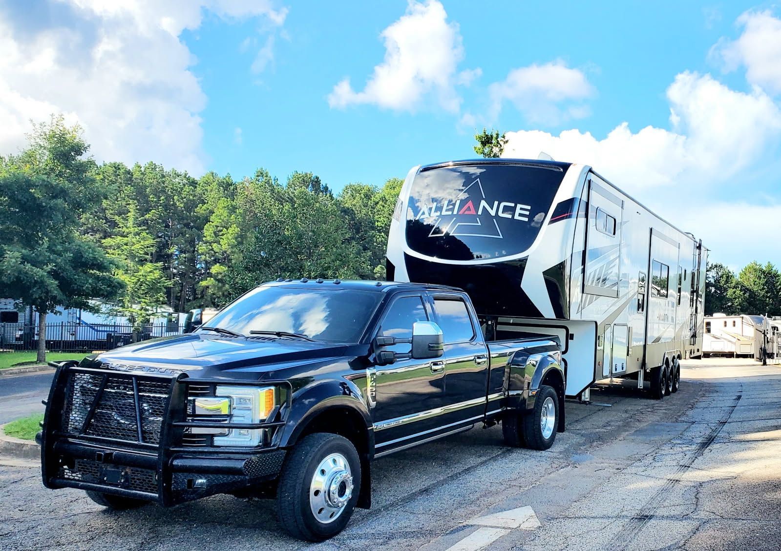 A black truck is towing a trailer on a gravel road.