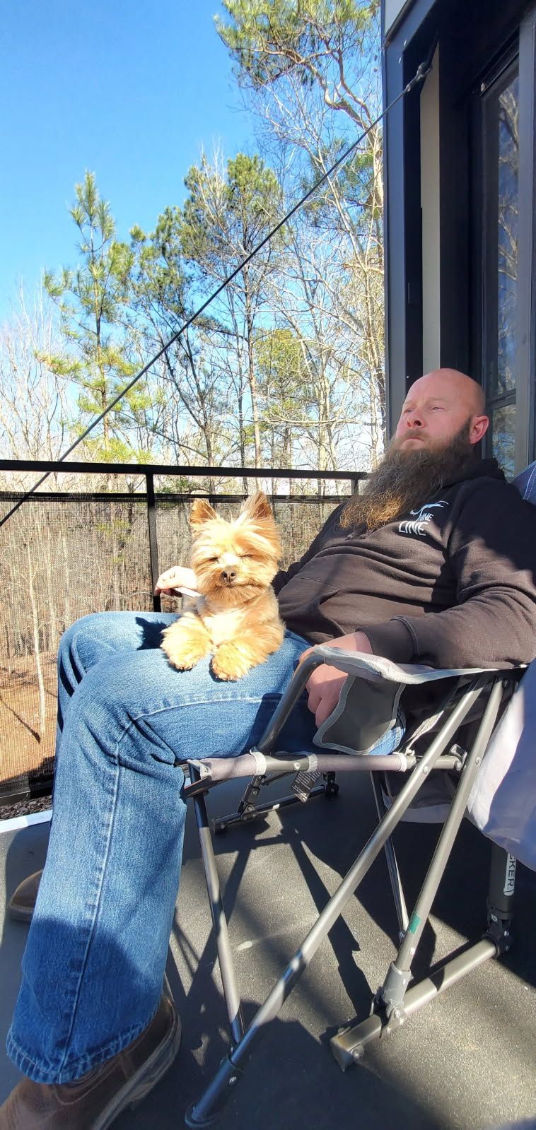 A man is sitting in a chair with a dog on his lap.
