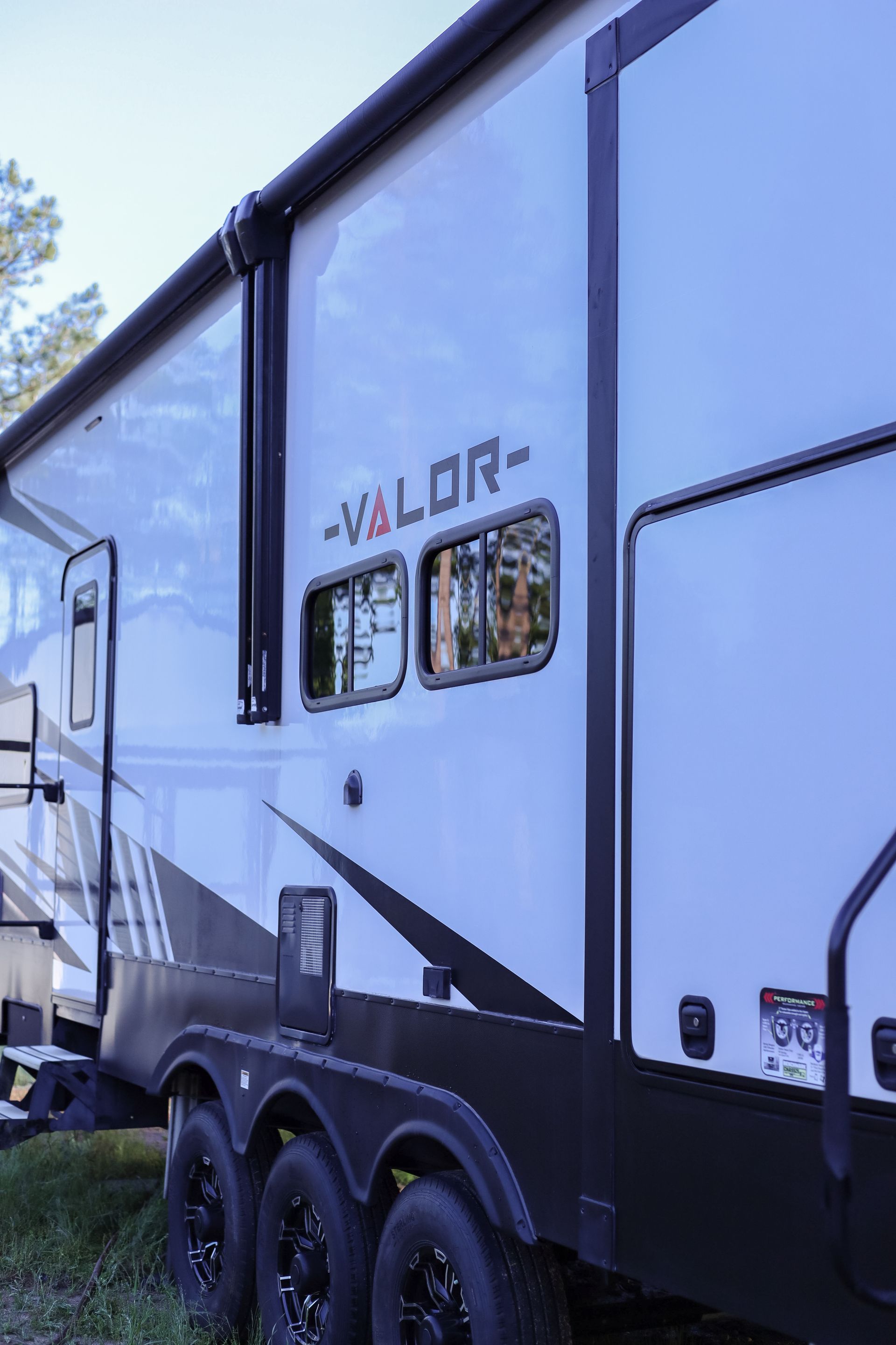 A white and black rv is parked in the grass.
