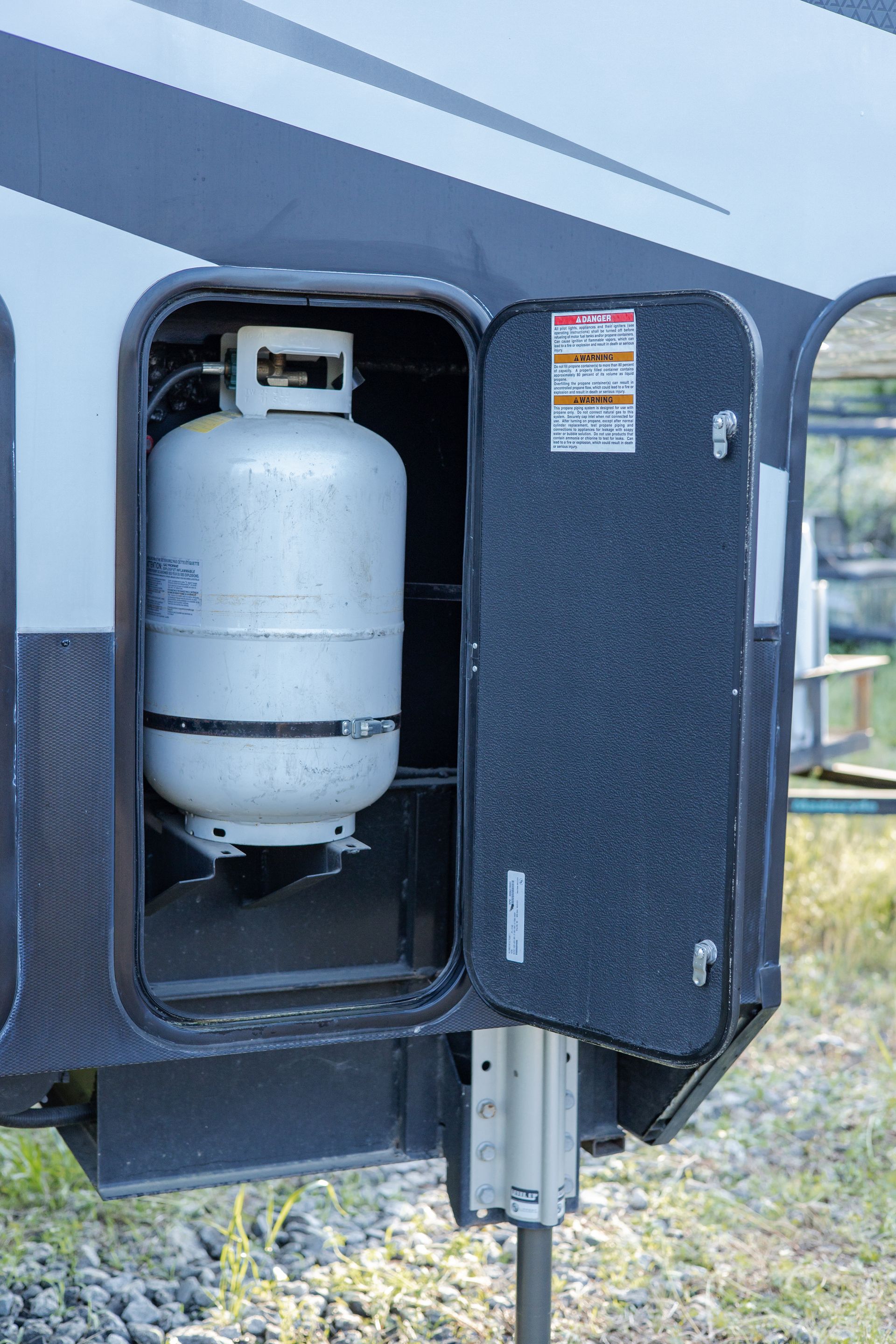 A propane tank is sitting inside of a trailer with the door open.