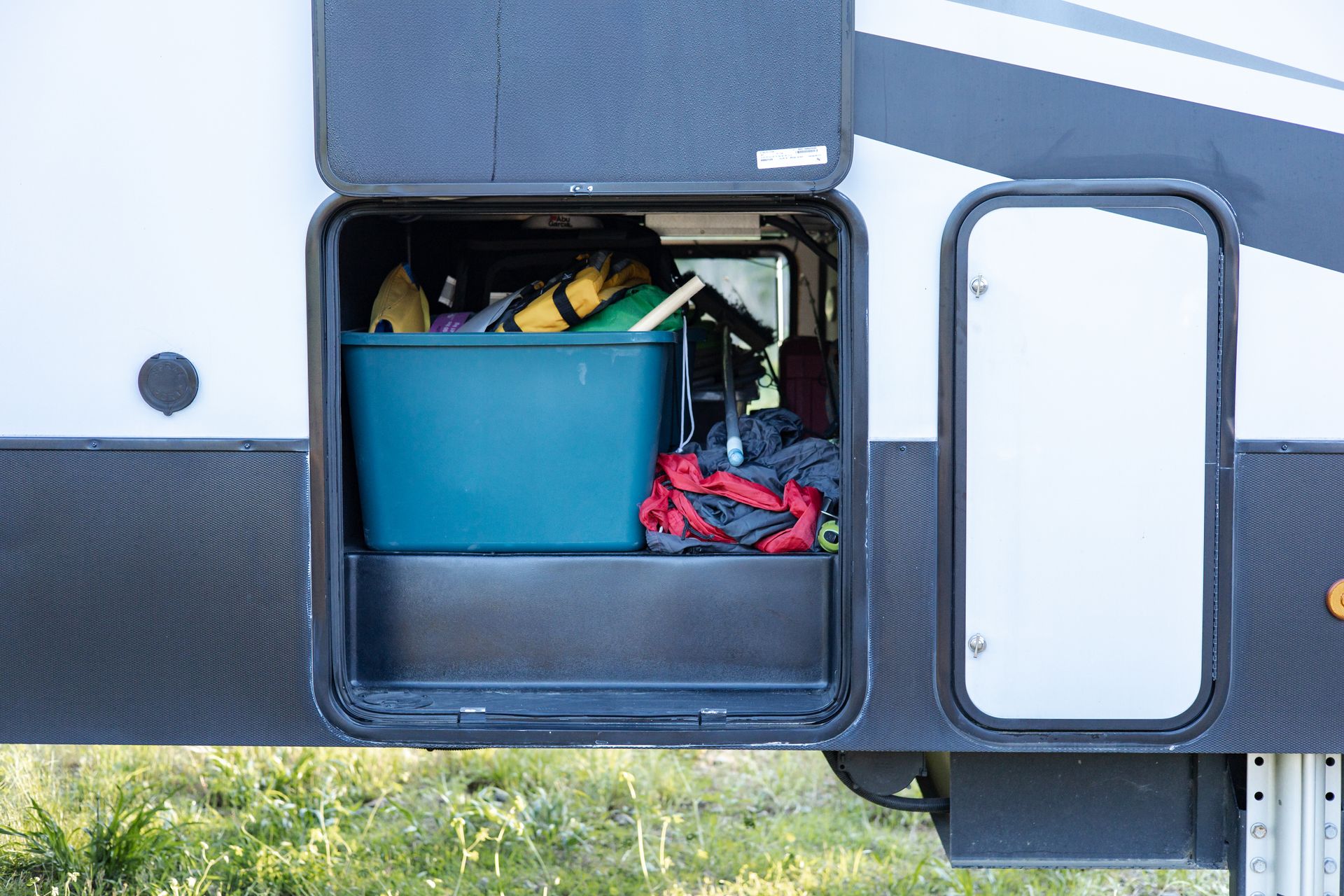 A rv with a blue bin in the back of it.