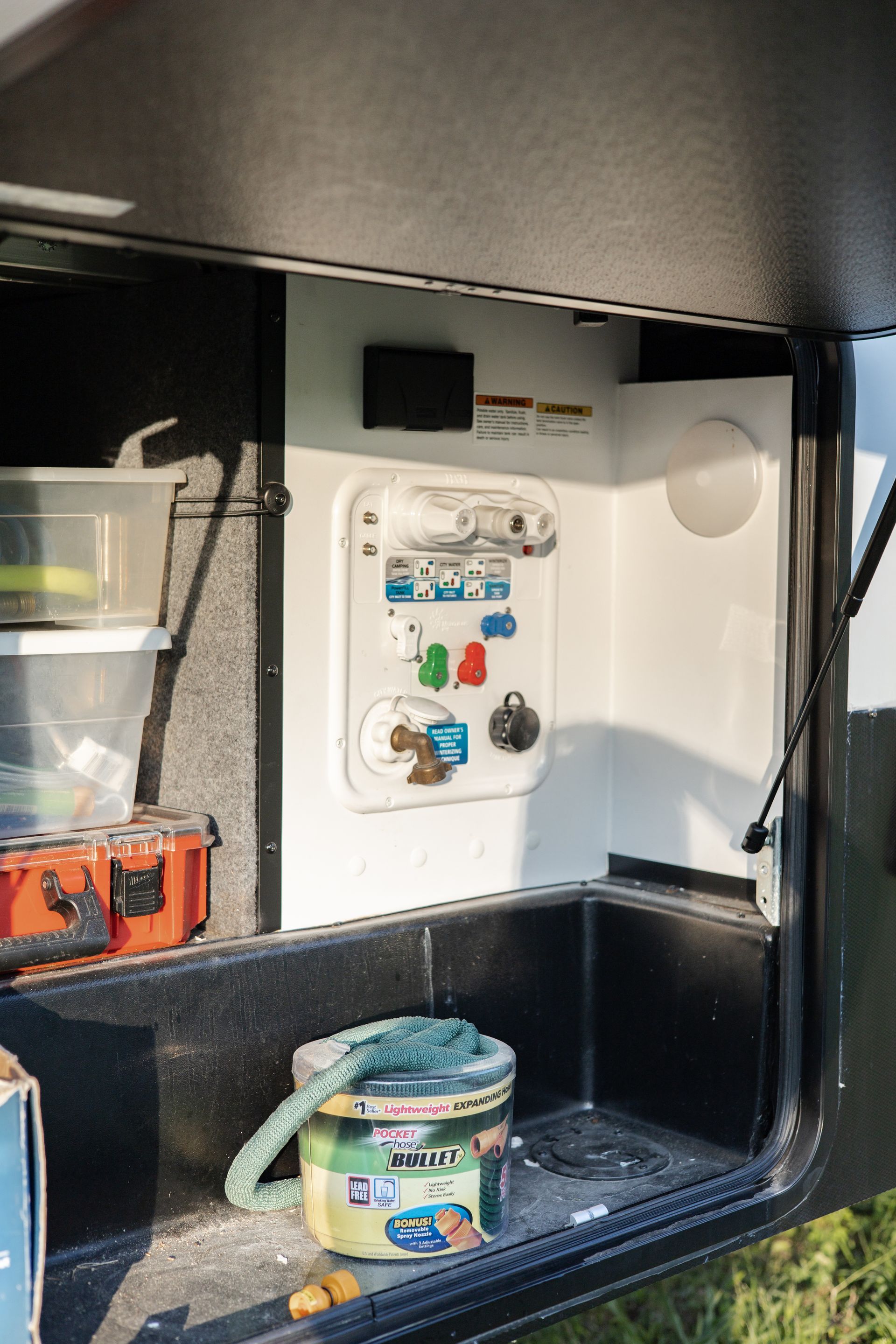 A bucket with a hose in it is sitting in the back of a trailer.