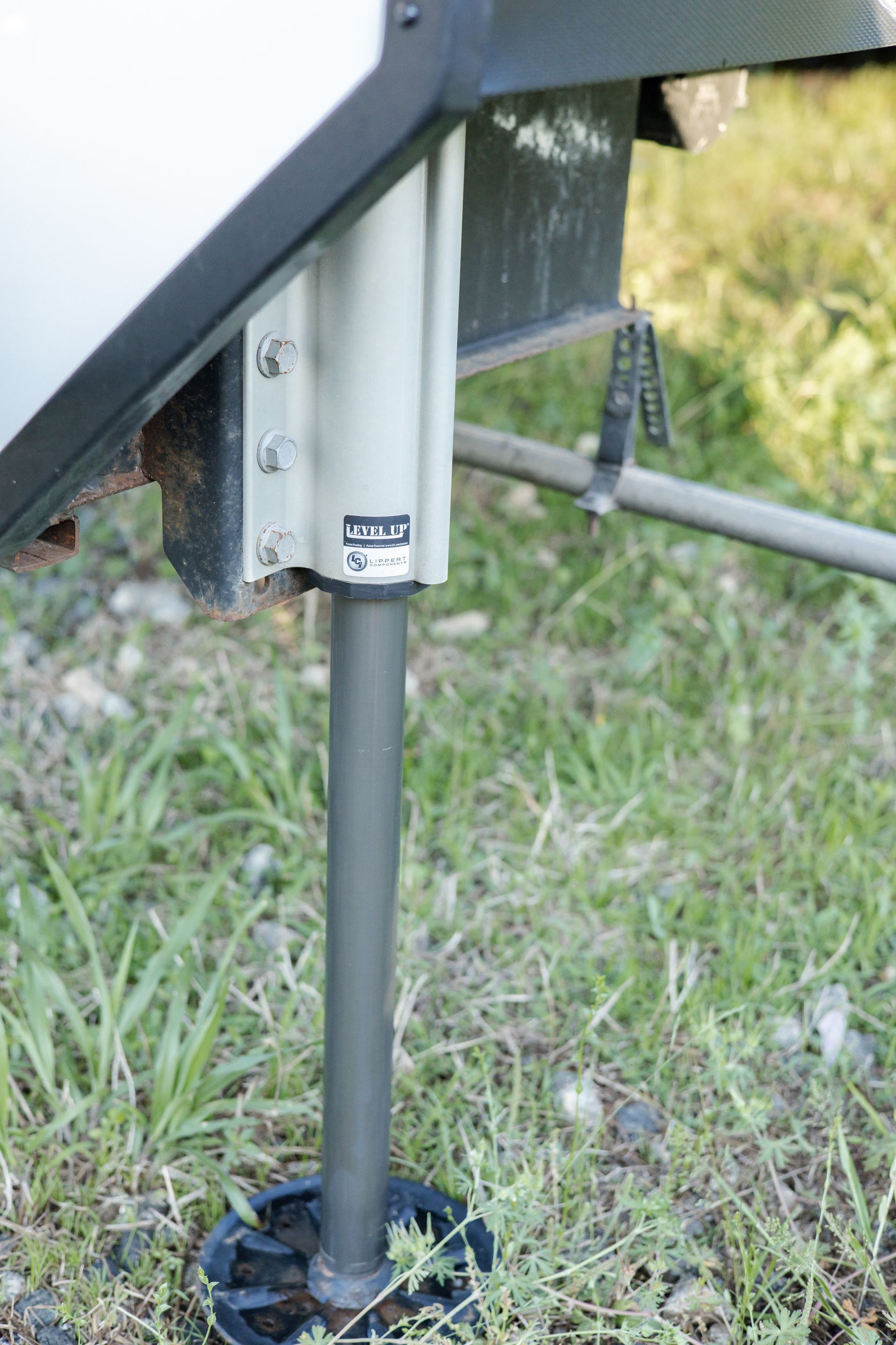 A metal pole is sitting in the grass next to a trailer.