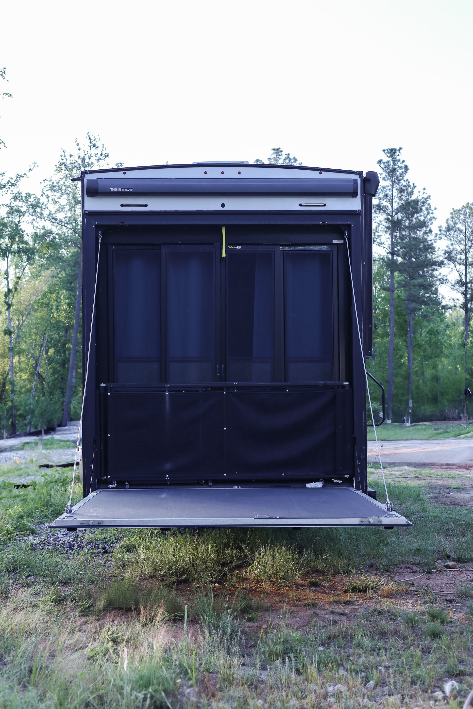The back of a rv is open and sitting in the grass.