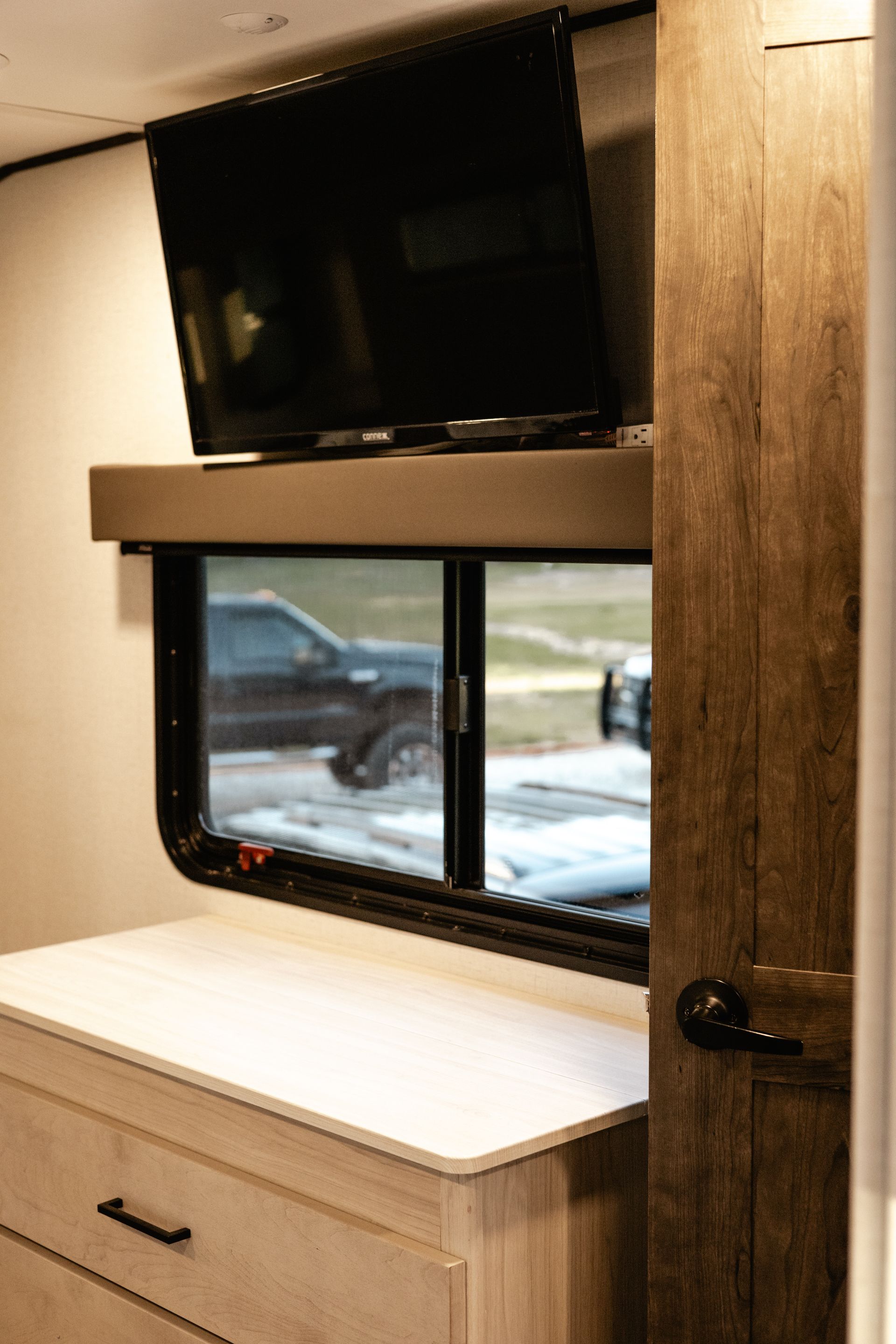 A television is mounted above a window in a rv.