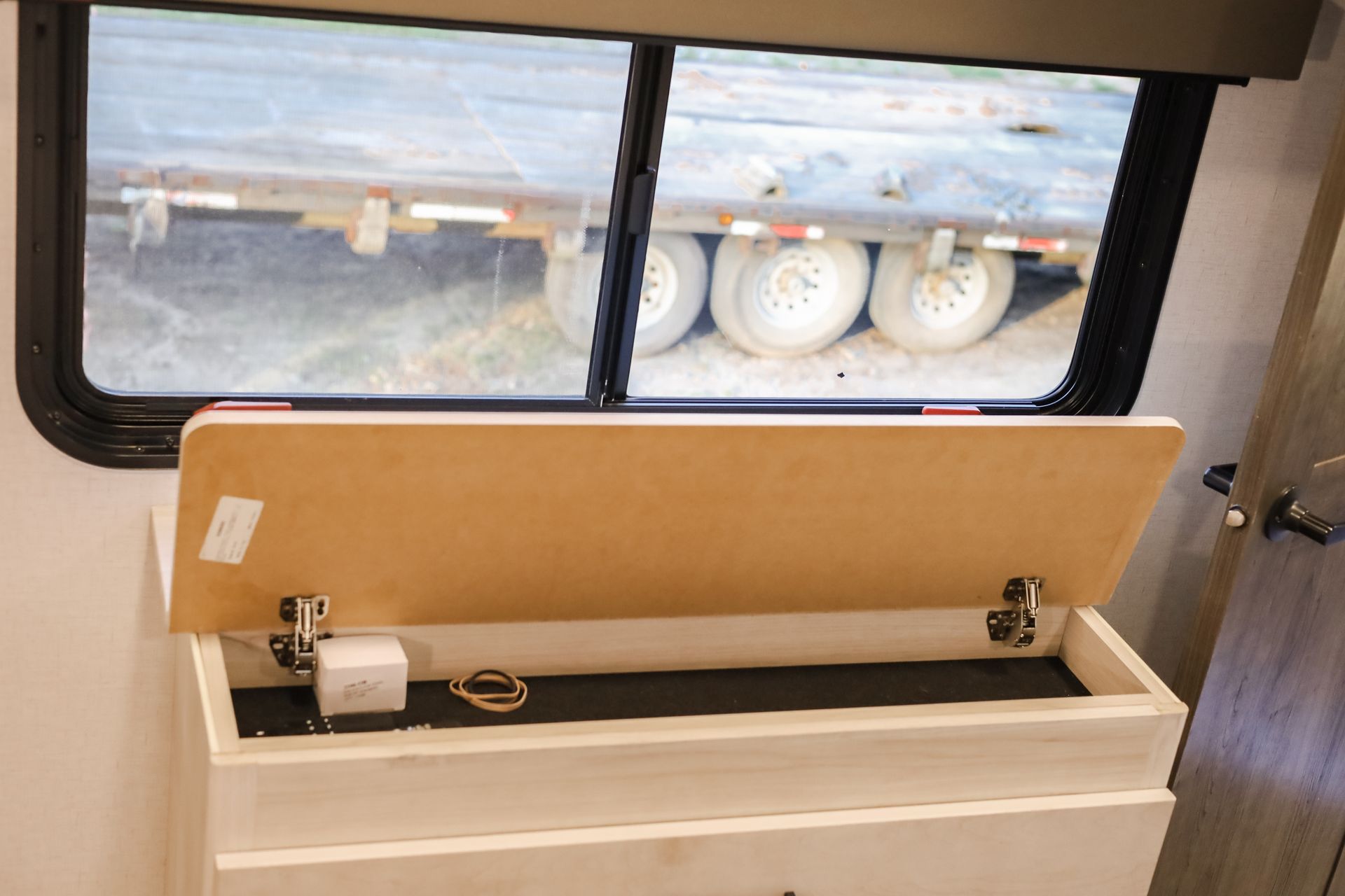 A dresser with the lid open and a window in the background.