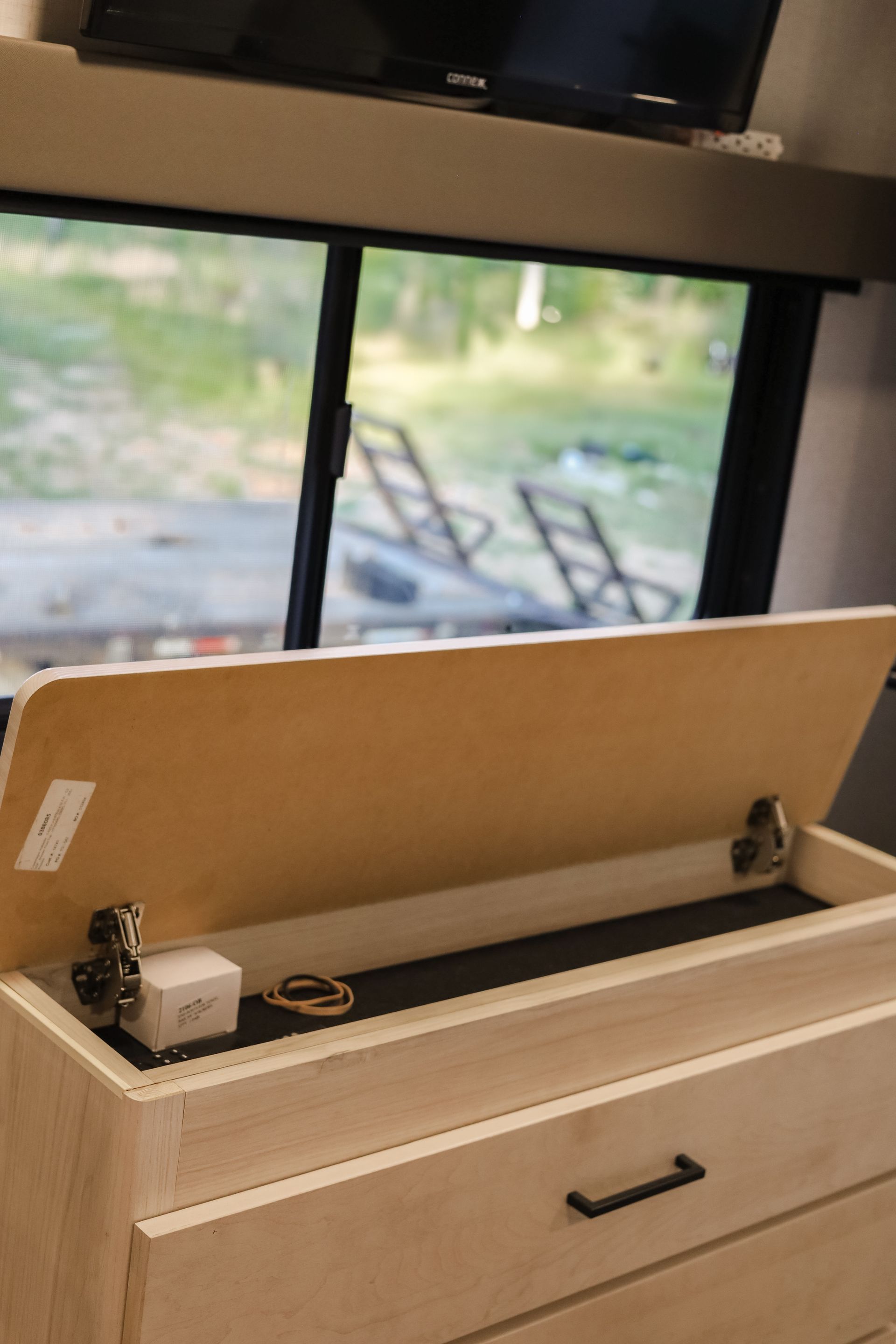 A dresser with a drawer open and a tv on the wall.
