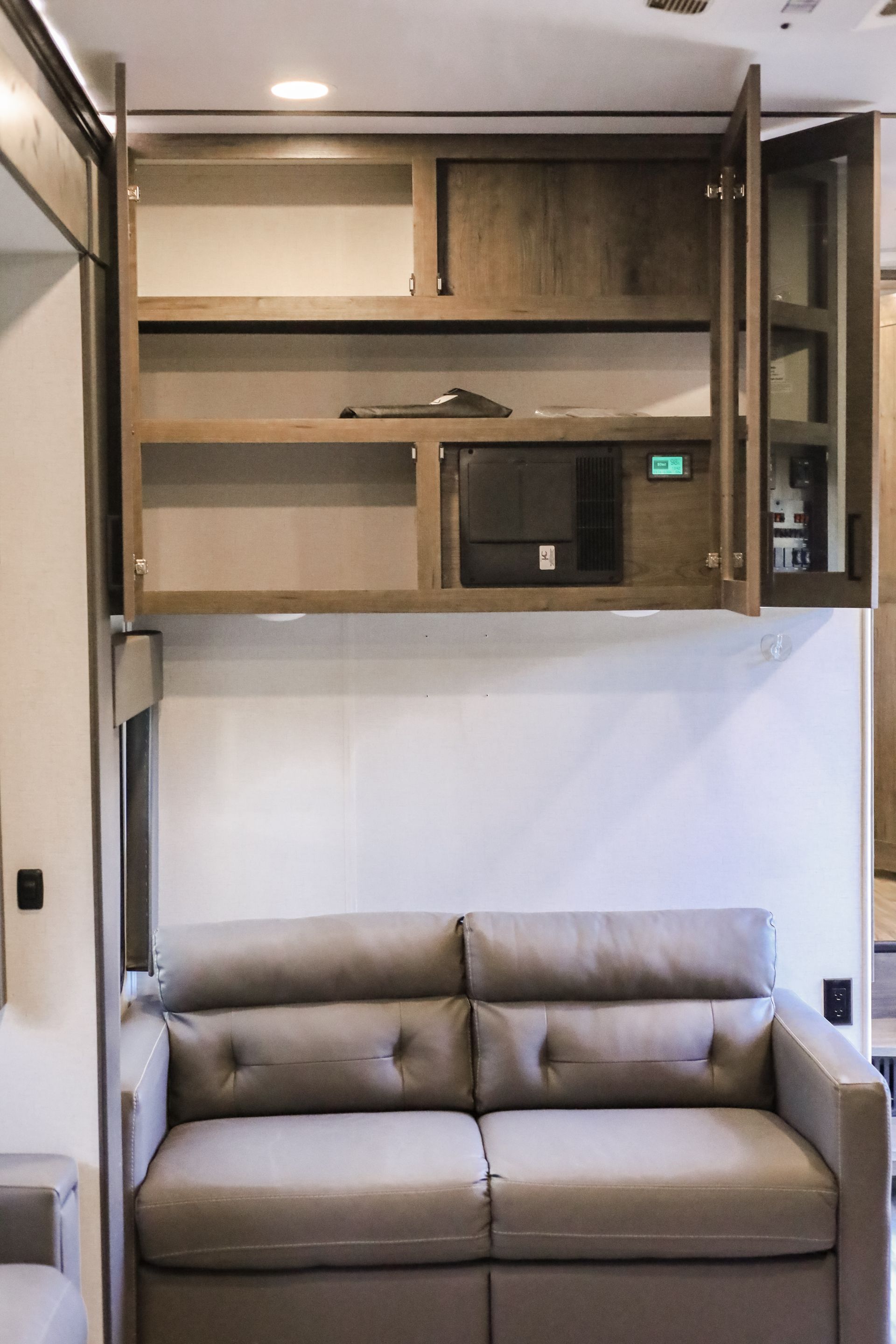 A living room with a couch and a shelf above it.