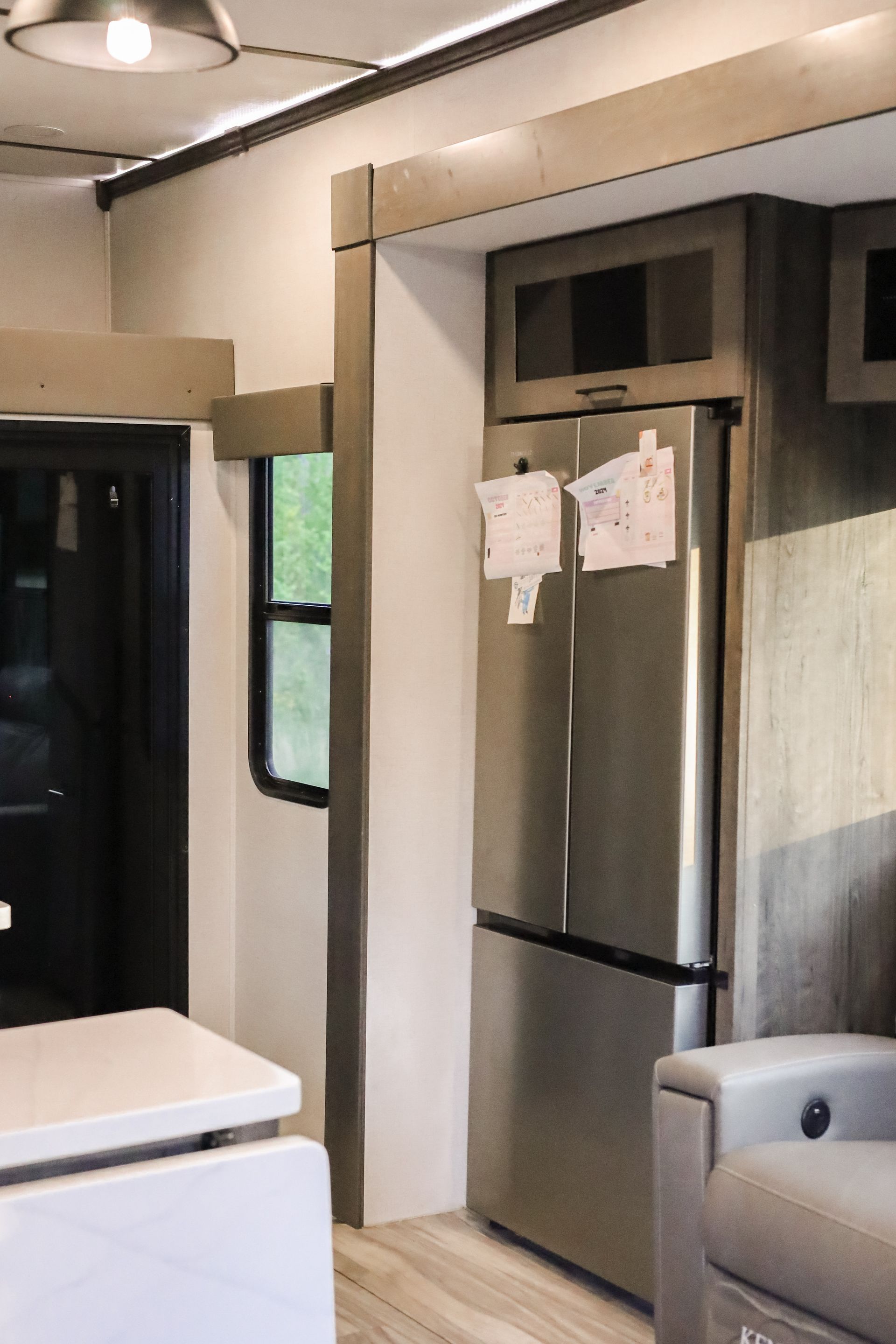 A stainless steel refrigerator is sitting in a living room next to a couch.