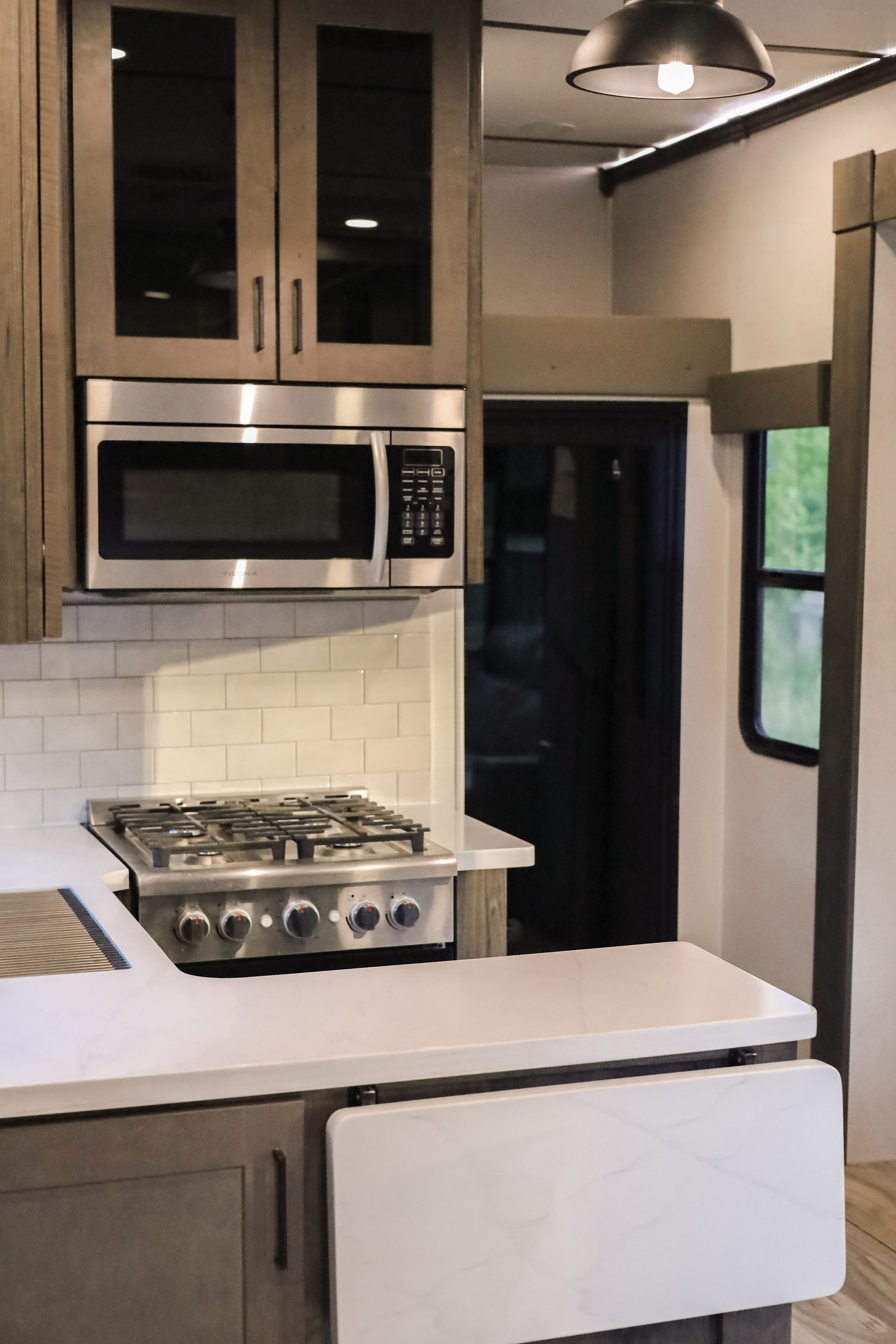 A kitchen with a stove , microwave , and cabinets.