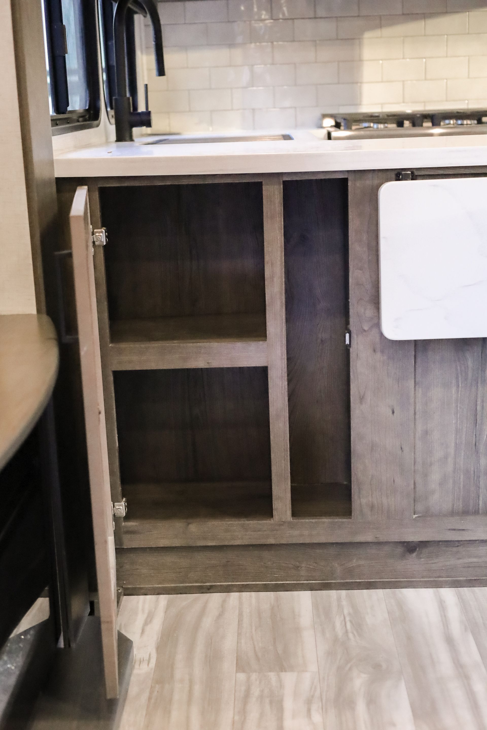 An open cabinet in a kitchen with a sink and stove