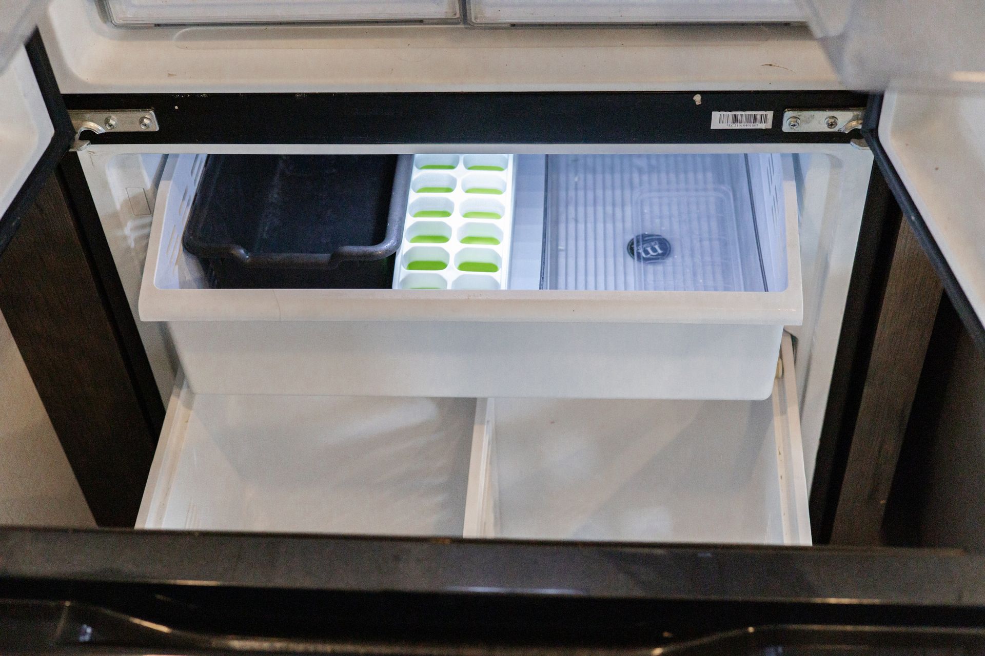 The inside of a refrigerator with ice cubes in it.