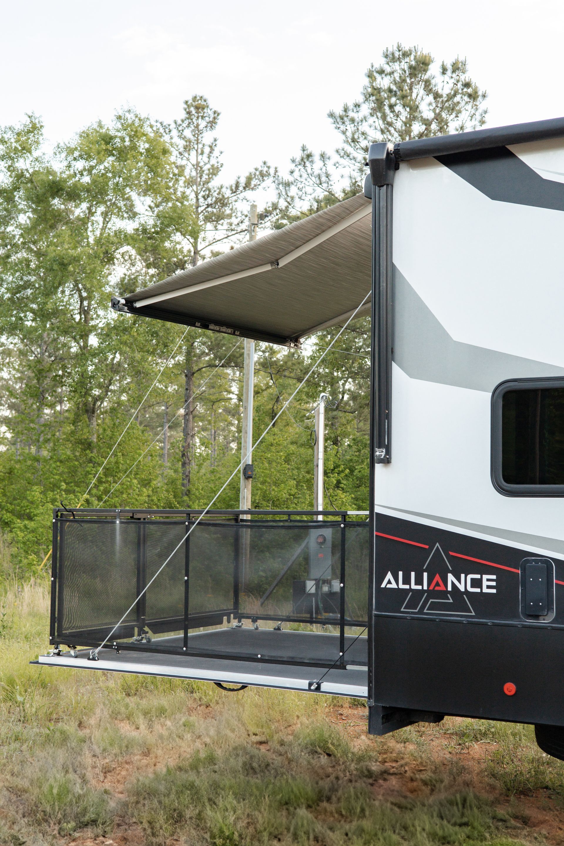 A rv with a canopy is parked in a grassy field.