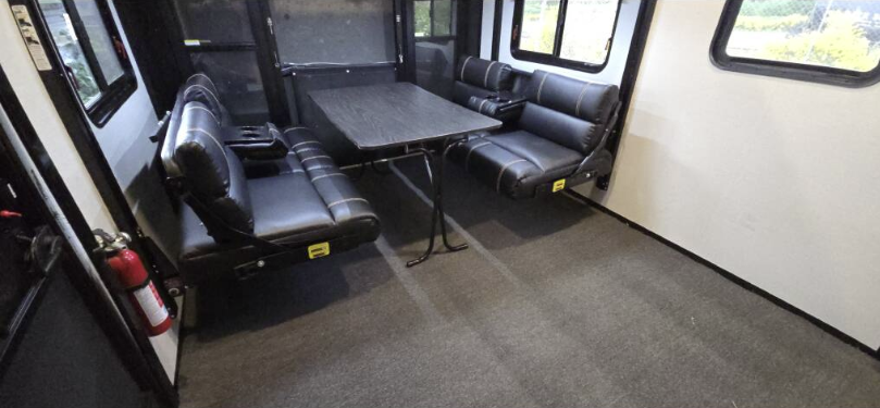 A living room in a rv with a table and chairs.