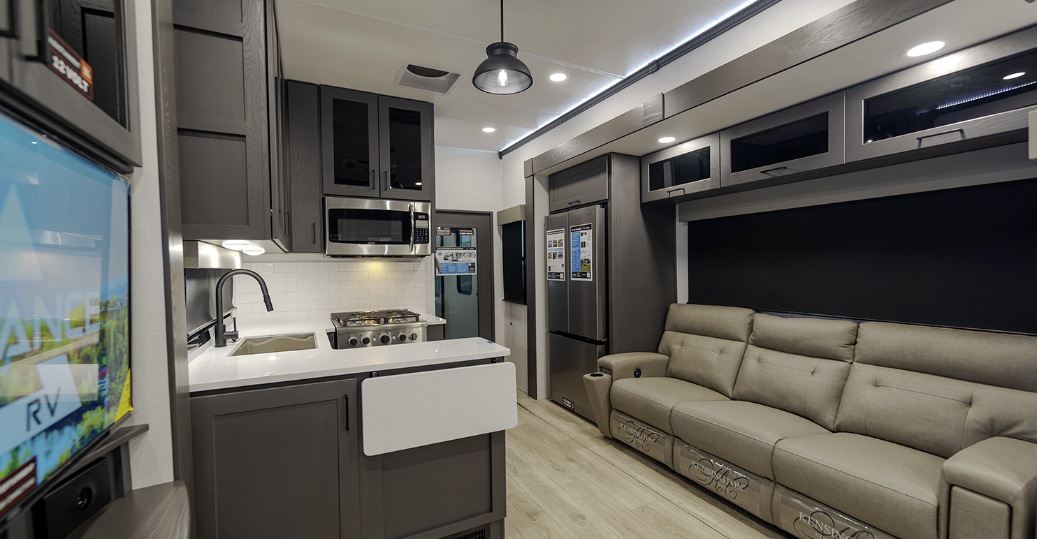 A living room with a couch , television , and kitchen.