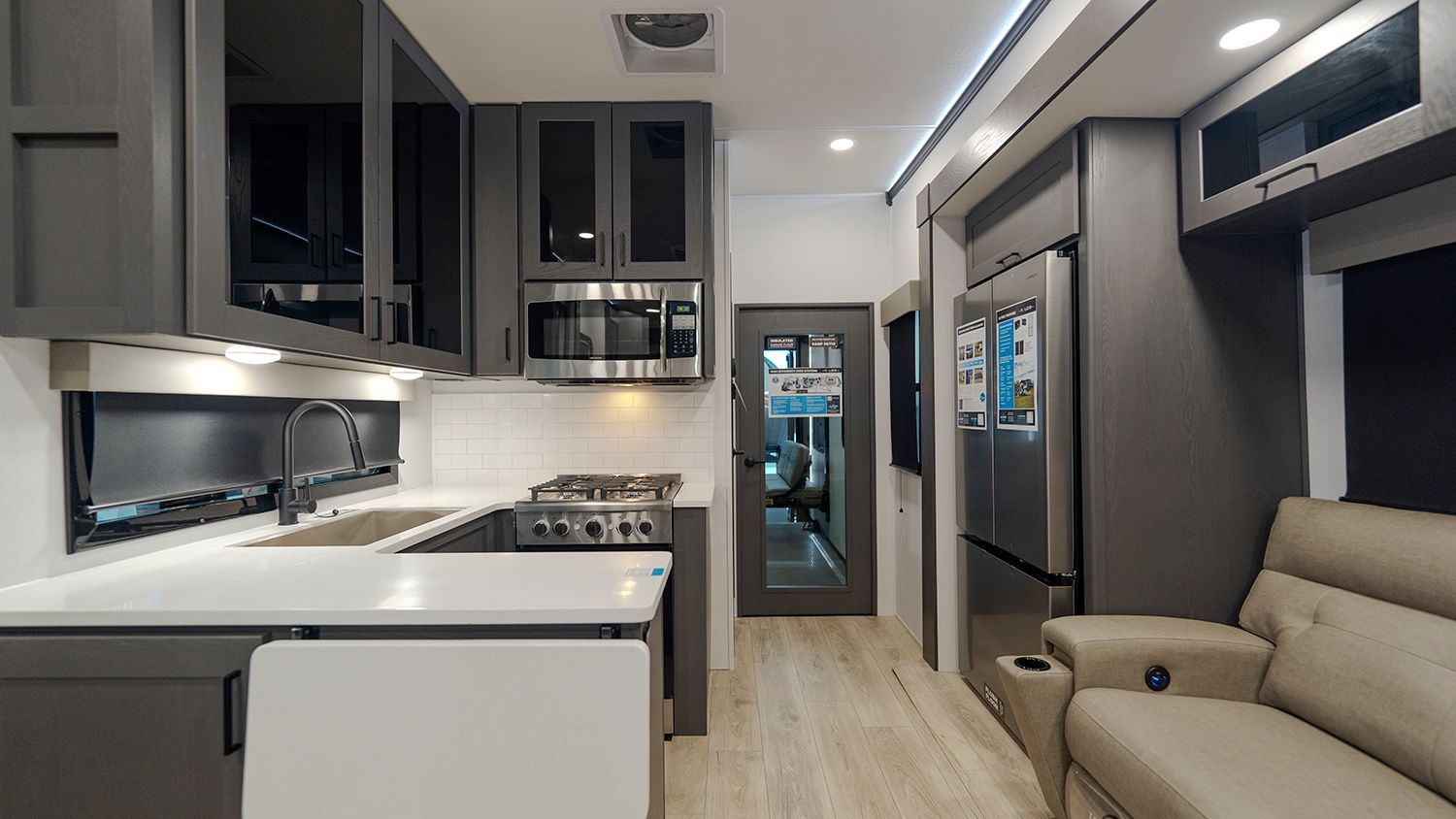 A kitchen with a stove , microwave , refrigerator and a couch.