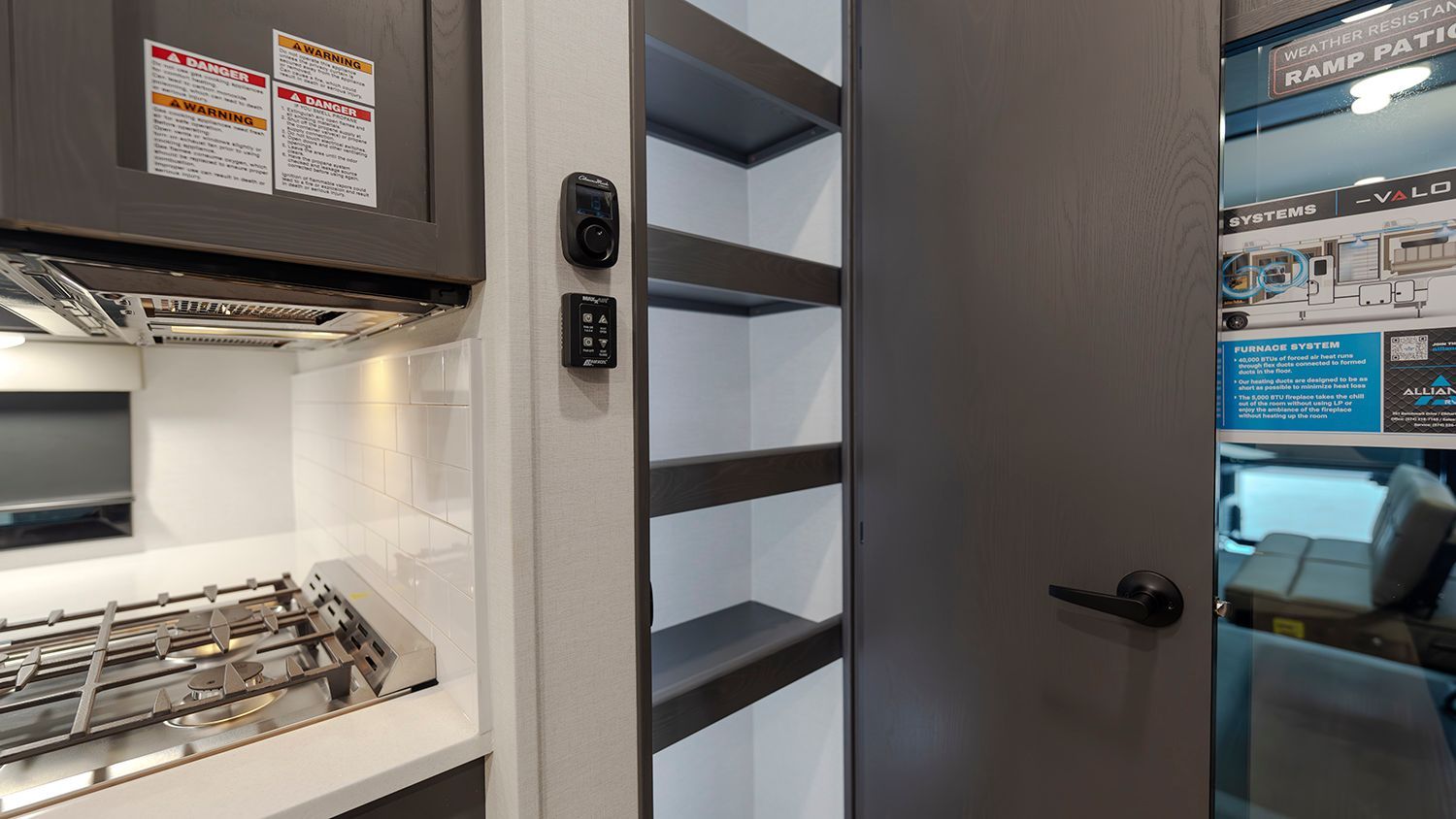 A kitchen in a camper with a stove and shelves.