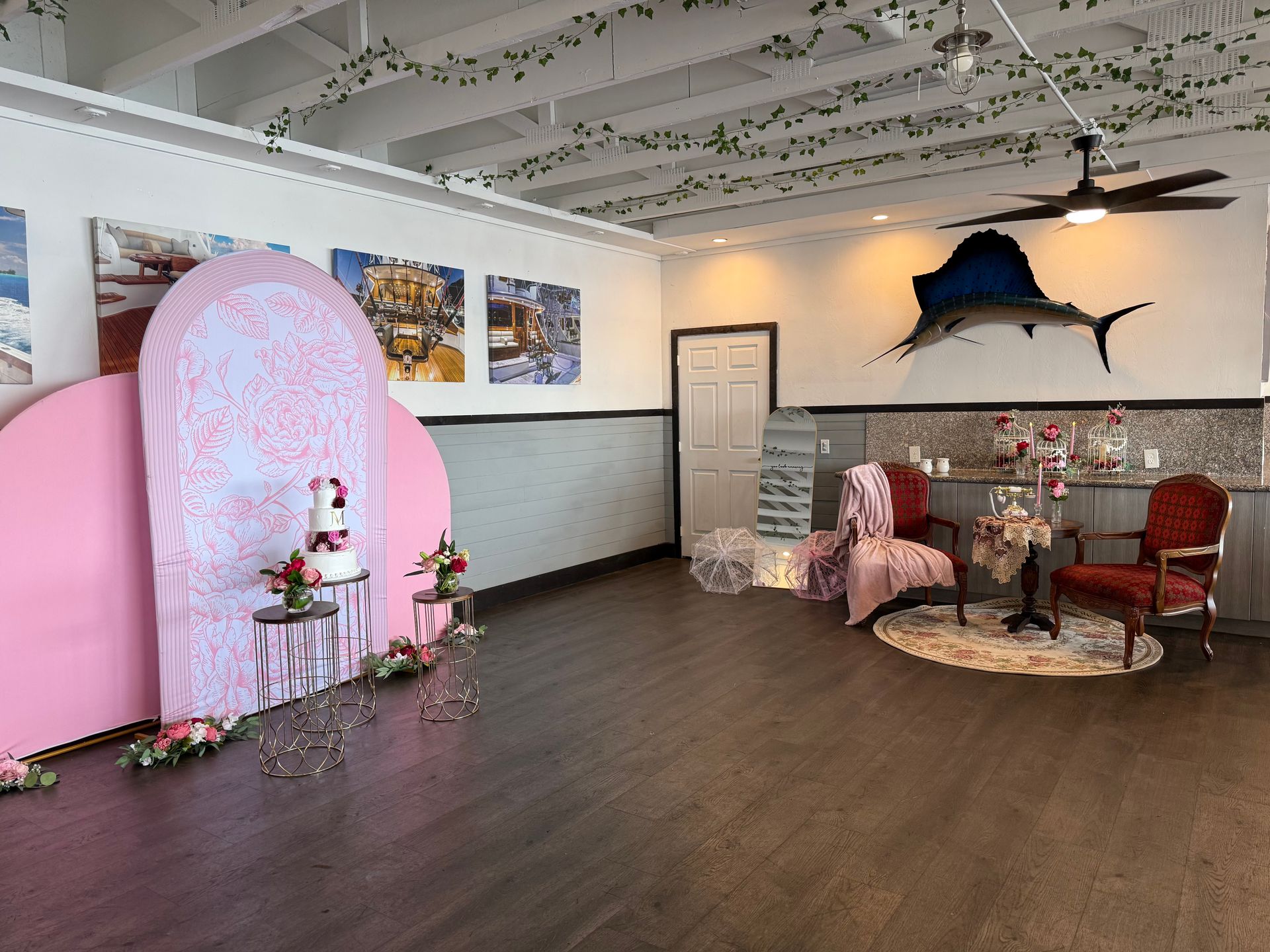 Event space with pink and white decor, cake table, and a mural of a fish.